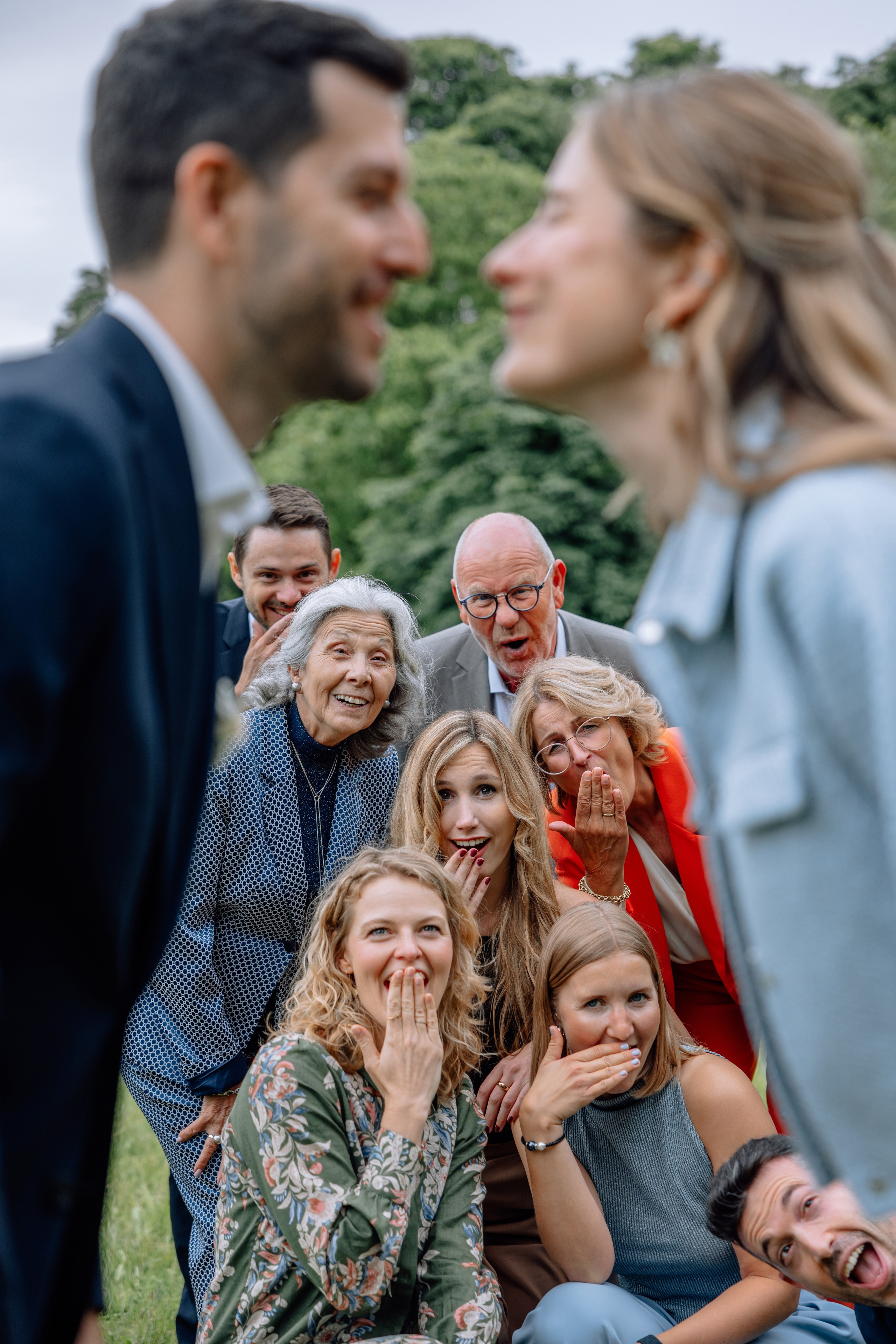 Gäste im Fokus, Brautpaar im Hintergrund unscharf – nähern sich für einen Kuss, Standesamt Schwabing.