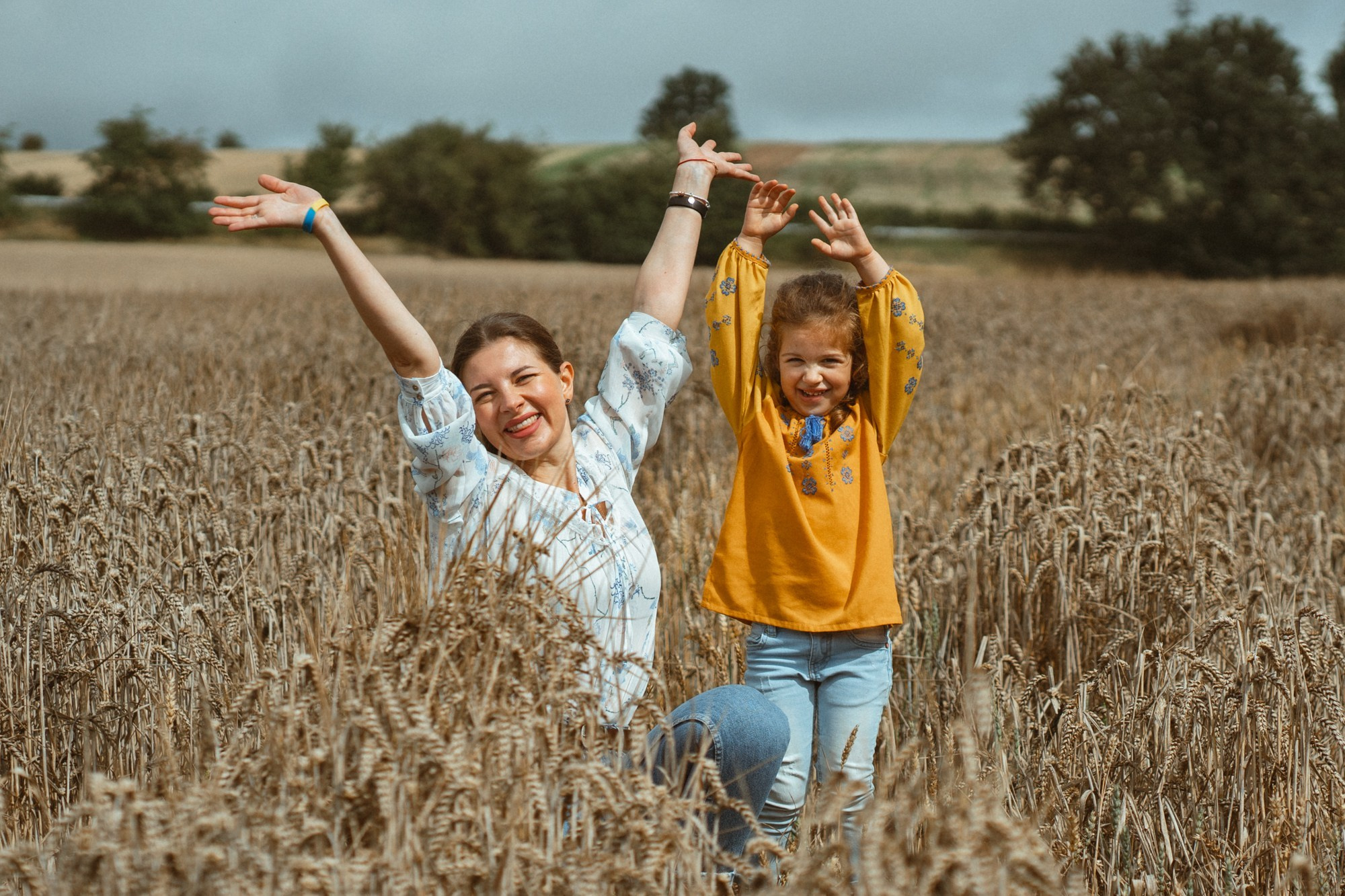 Семейная фотография в поле — мама и дочка радуются в золотых колосьях