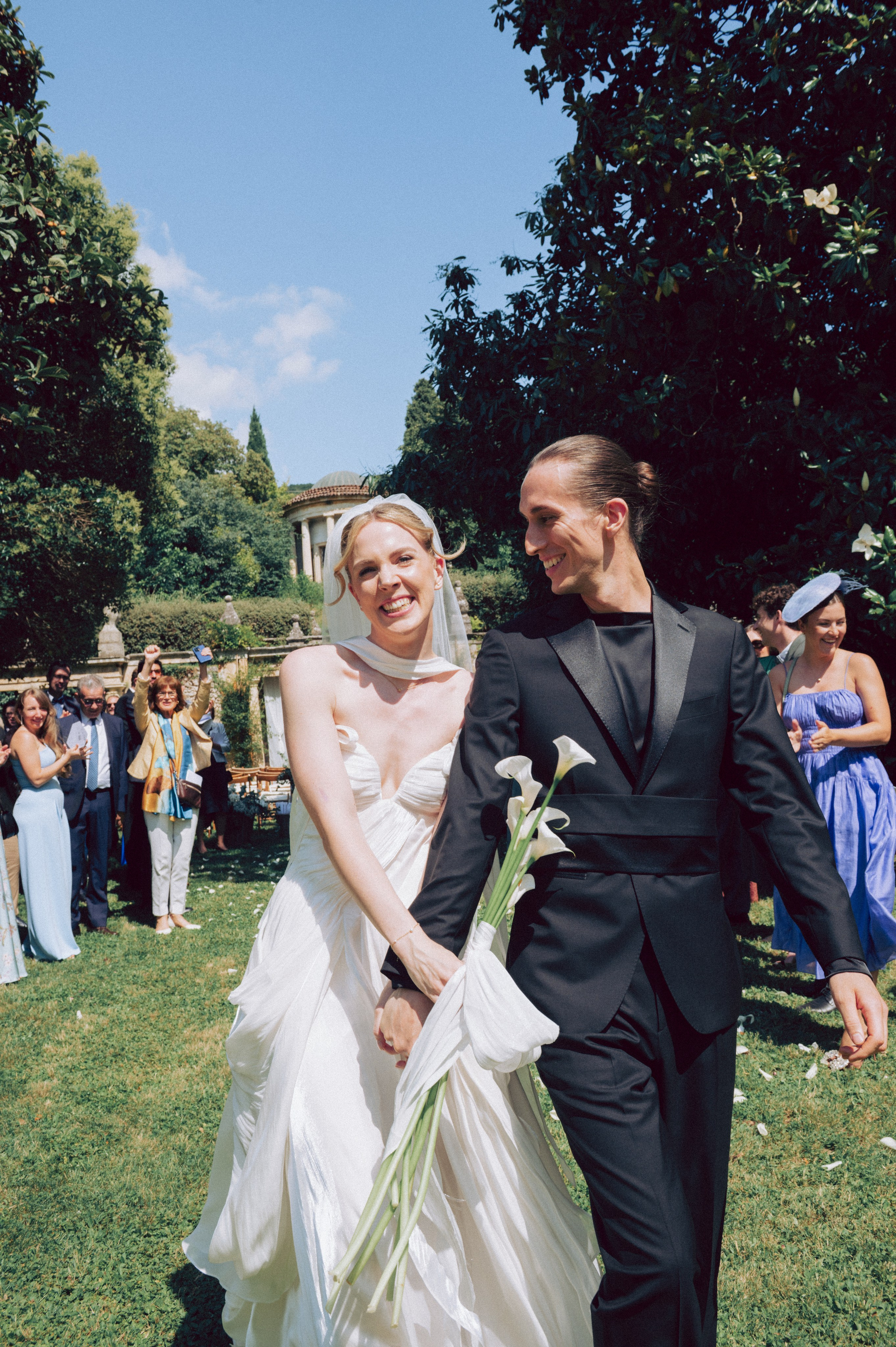 Fotografia spontanea degli sposi che camminano mano nella mano tra gli invitati durante un destination wedding in Veneto. Fotogrago matrimoni in Veneto