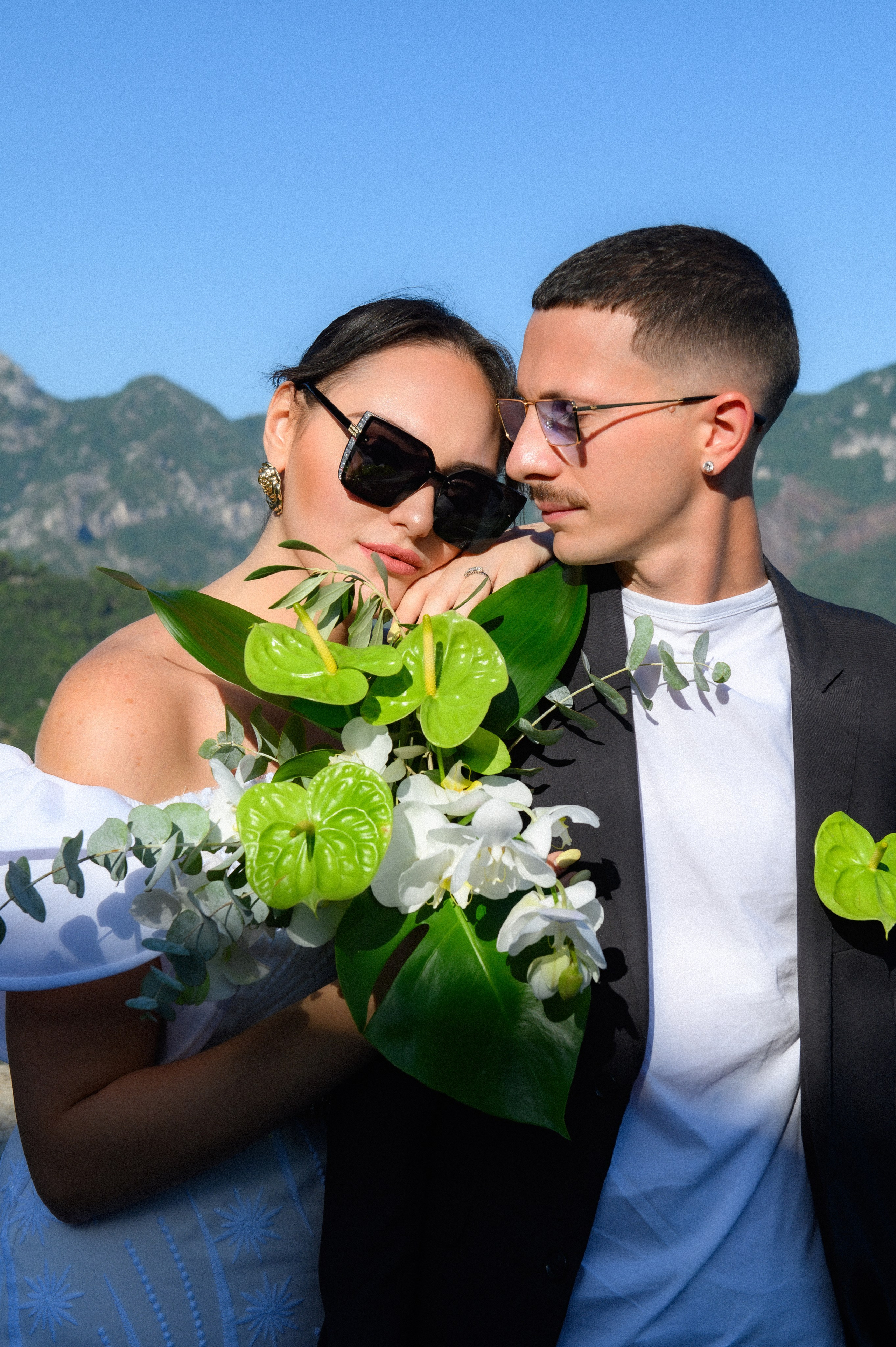 Sposa e sposo in un momento intimo e naturale a Ravello, fotografati con le montagne della Costiera Amalfitana sullo sfondo e un bouquet tropicale. Fotografo matrimoniale su Costiera Amalfitana