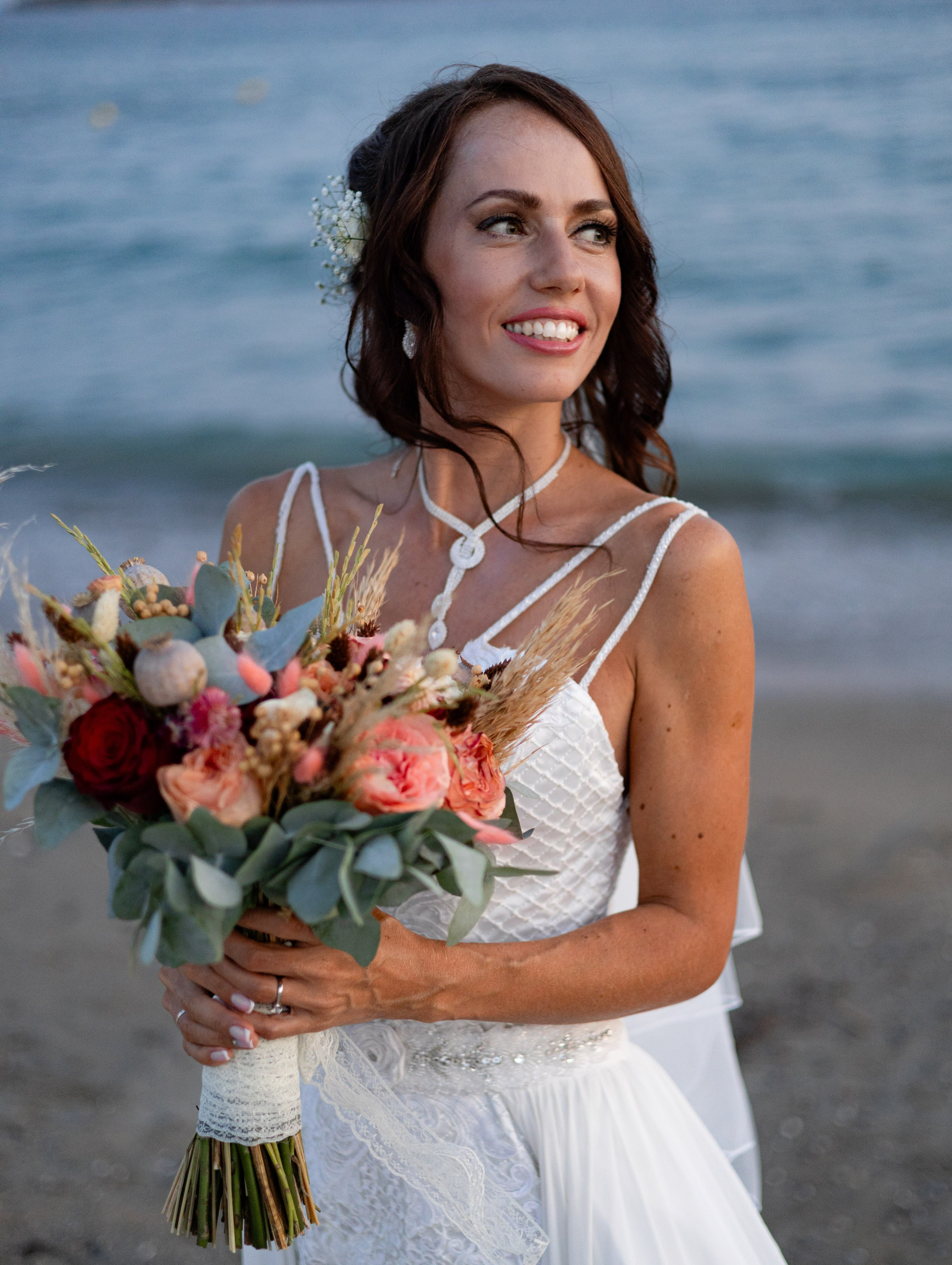 Bride holding her wedding bouquet by the sea