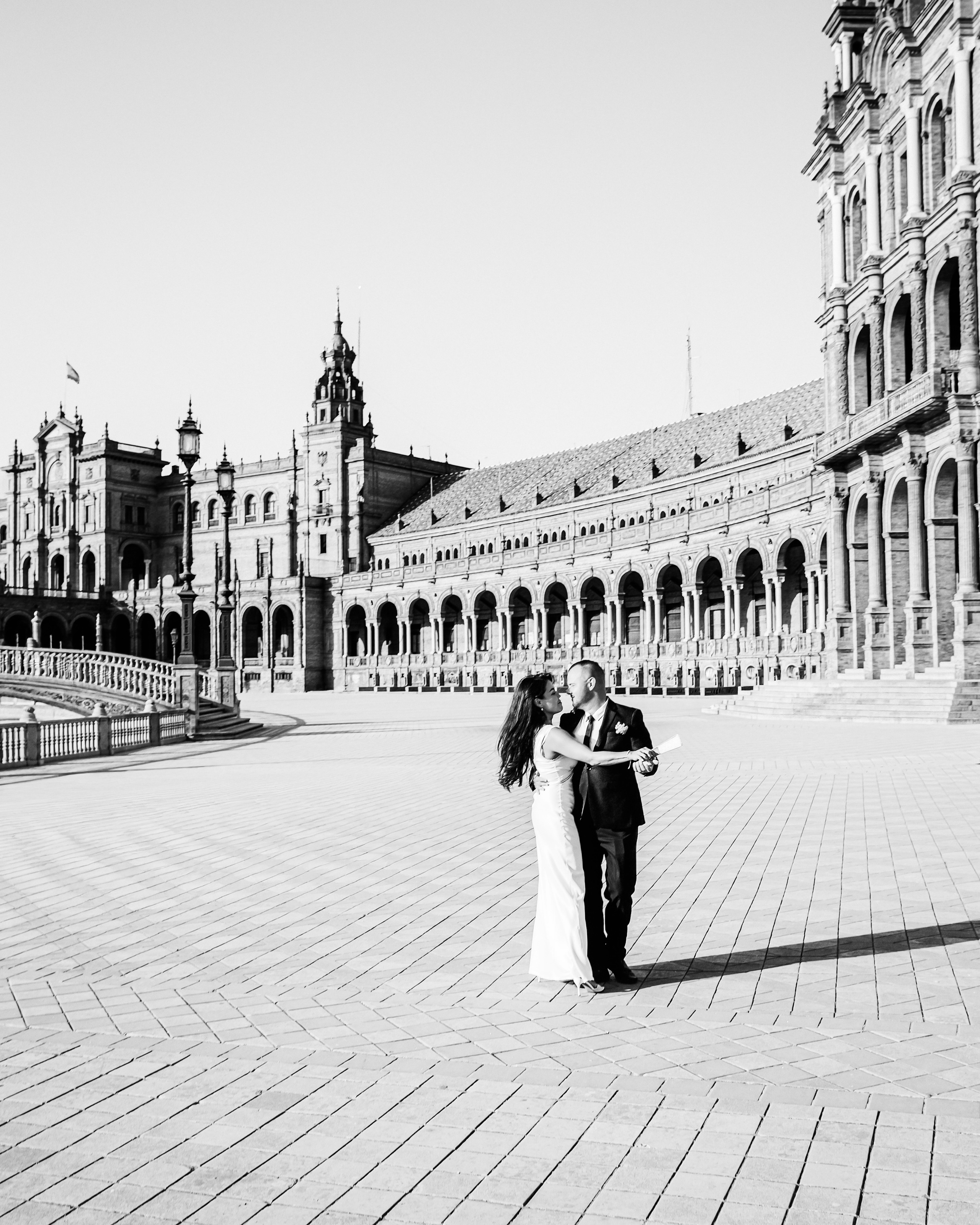 Elegant black-and-white wedding photo of a couple dancing in the grand plaza of Plaza de España, Sevilla, Spain — an iconic and romantic location ideal for timeless wedding photoshoots in Seville and southern Spain.
