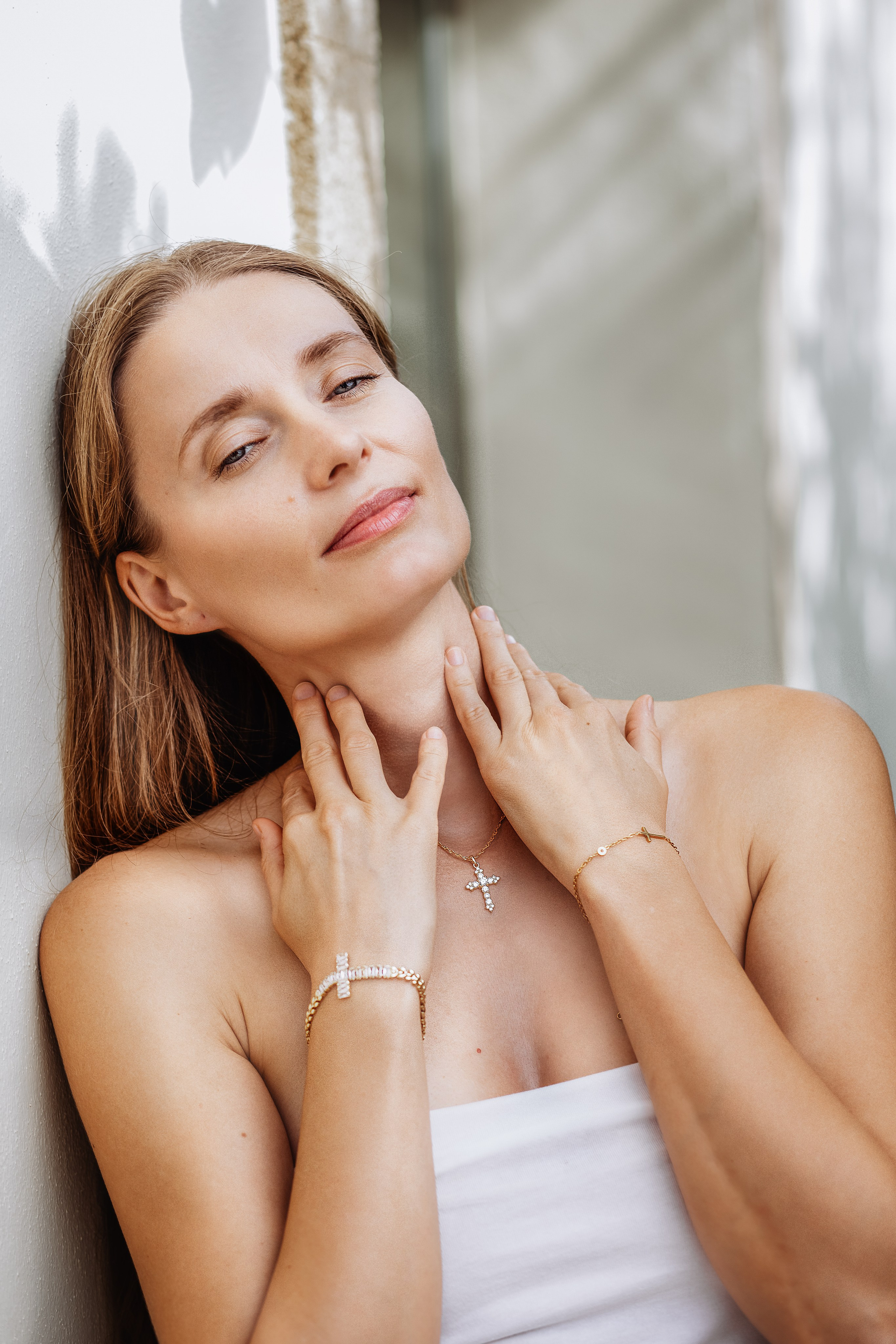 Elegant brand portrait of a woman showcasing fine jewelry with cross details, captured in soft natural light during a product photoshoot in Valencia, Spain — perfect for brands seeking high-end content, product, or lifestyle photography in Valencia and across Spain.