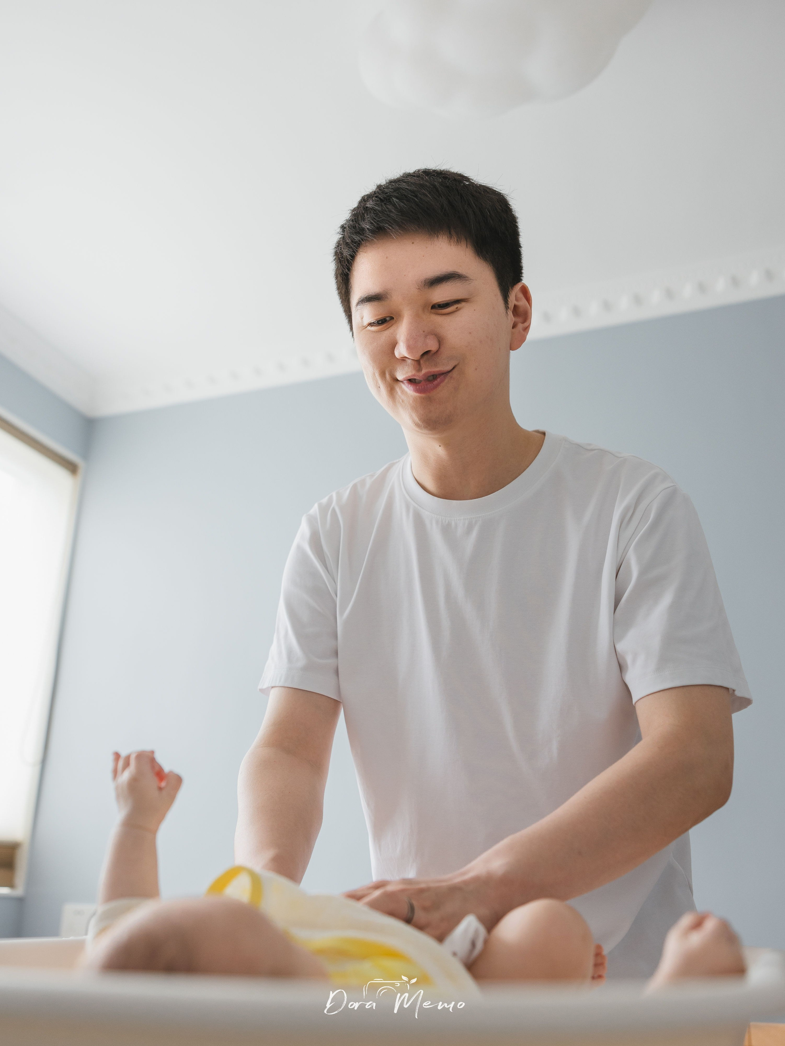 In a family photoshoot, a Shanghai father is changing his newborn's diaper.
