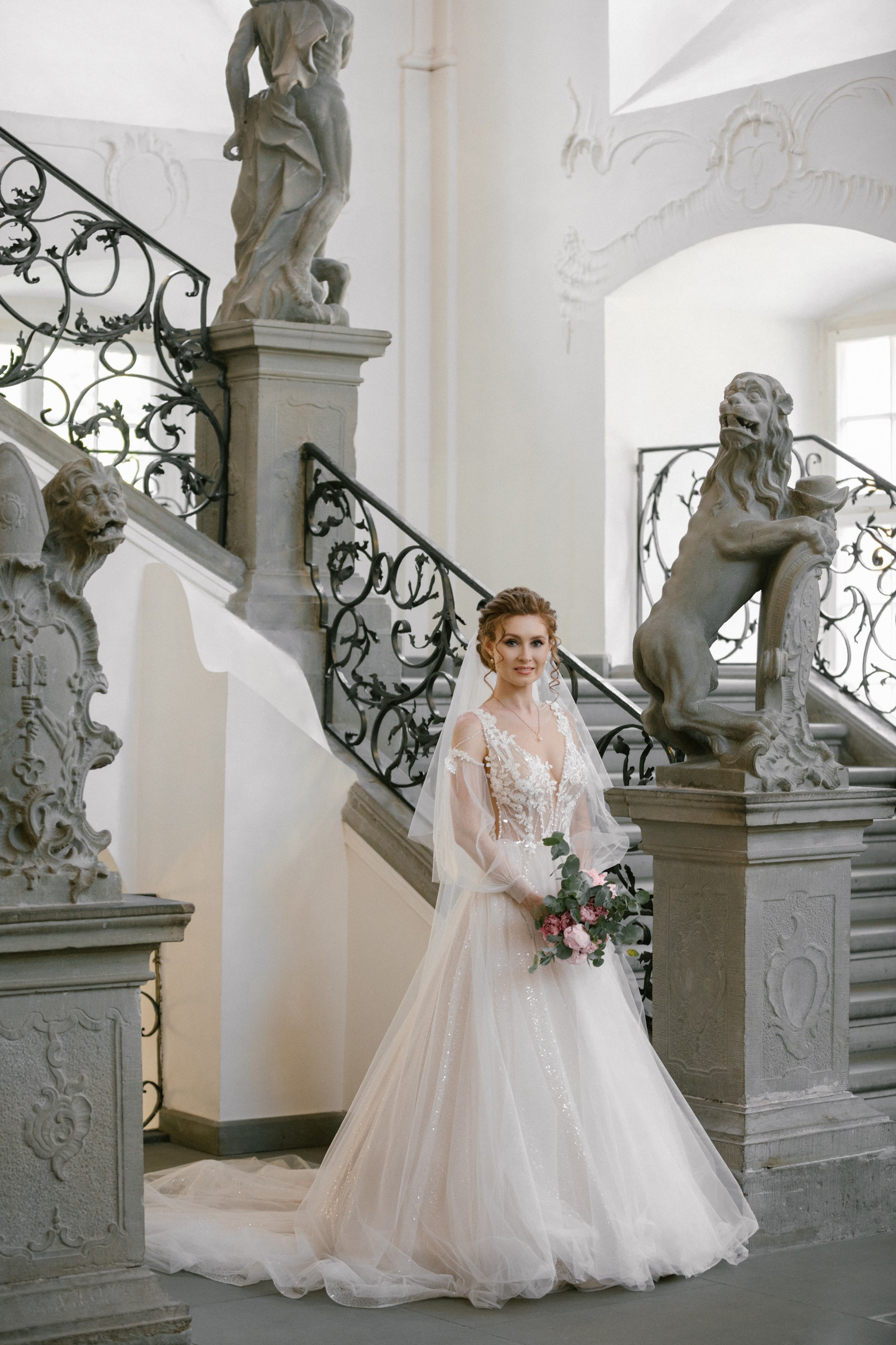 Bride standing near staircase lion sculpture at Neues Schloss Meersburg