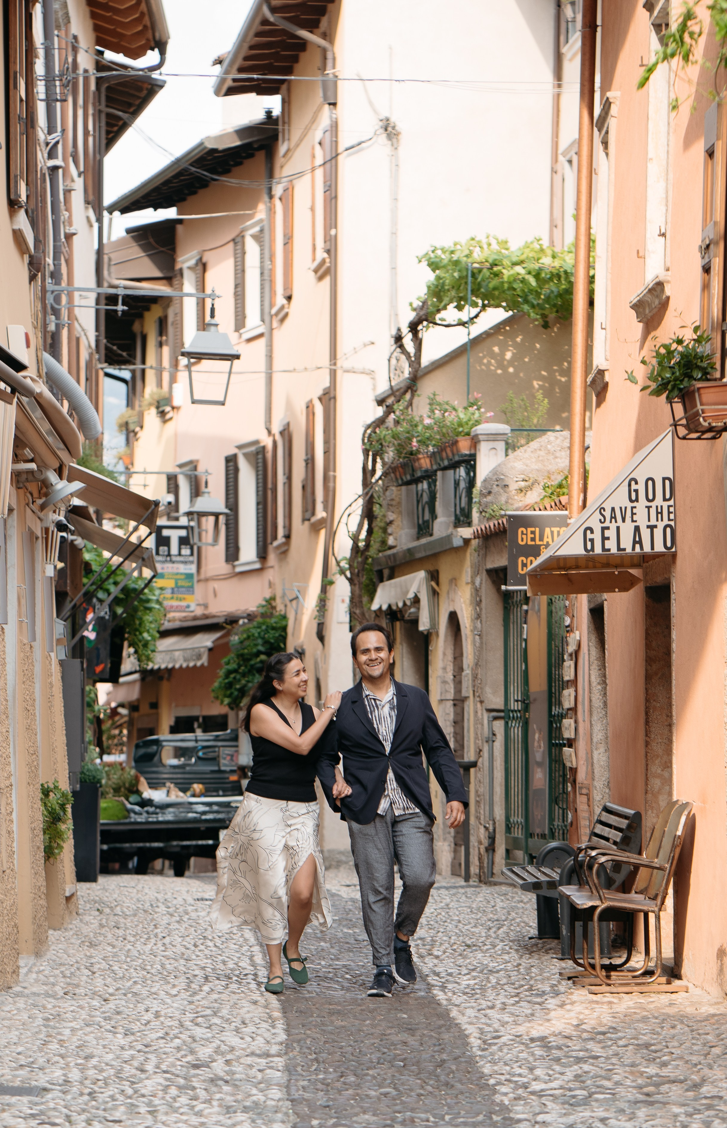 Couple walking hand in hand after a surprise proposal in Malcesine by the lake.