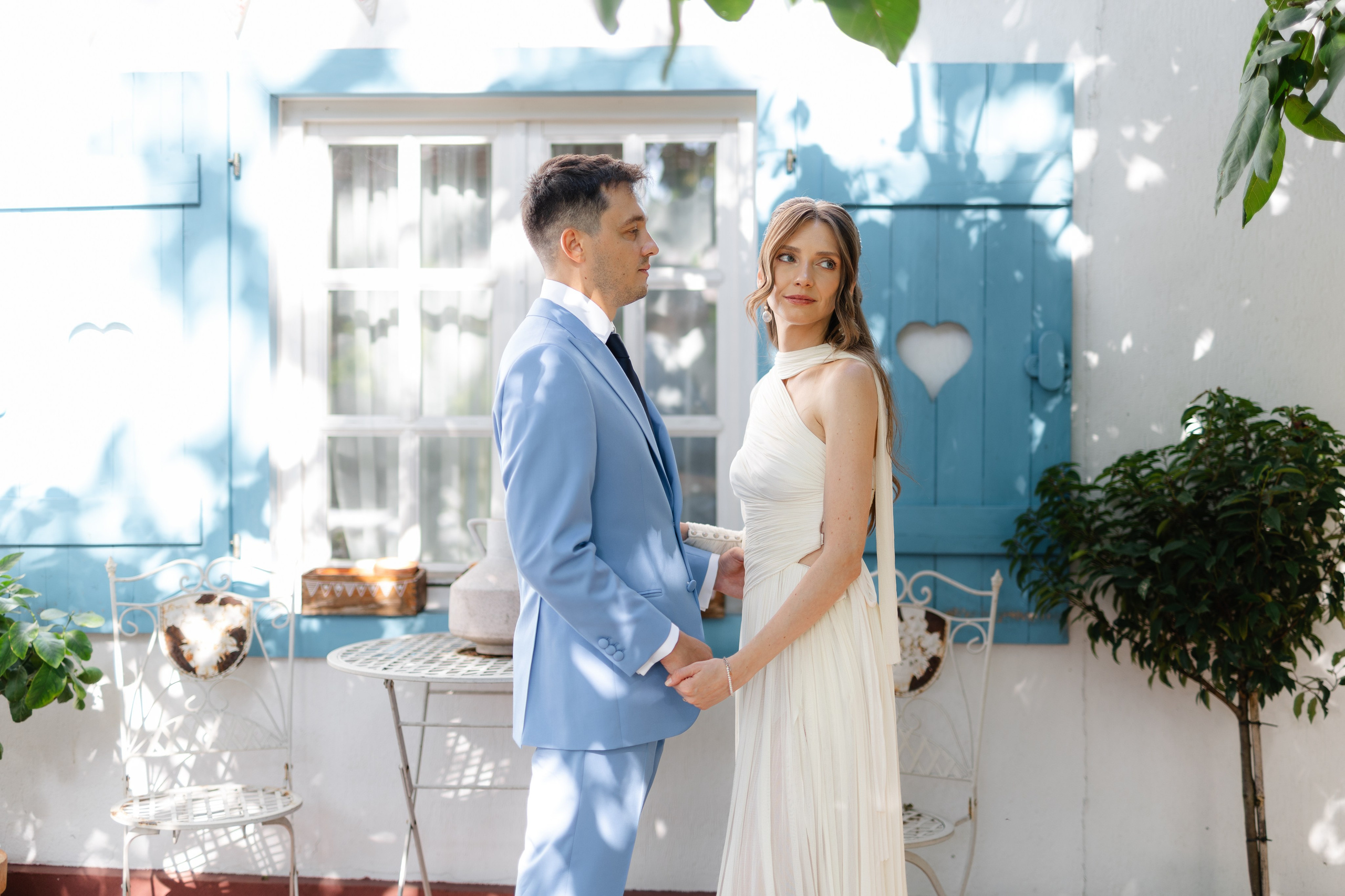 A couple posing for their photographs on their wedding day, the bride is looking away and the groom is looking at the bride.