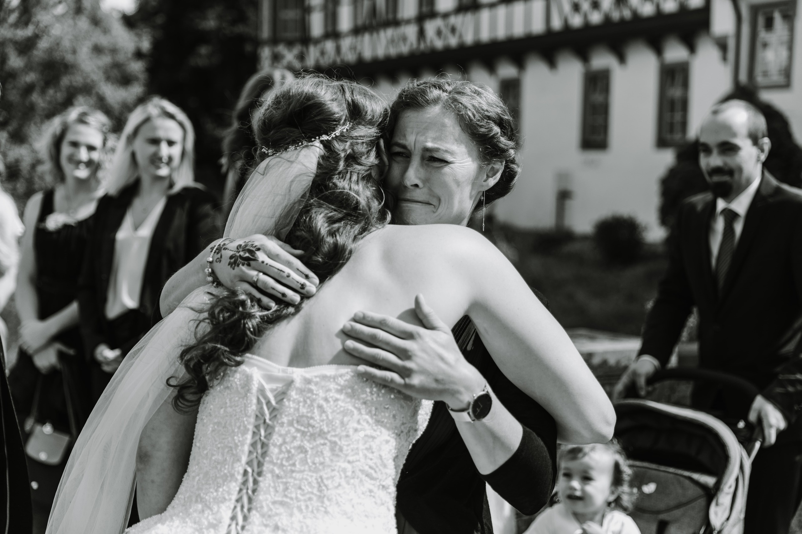 Schwester der Braut umarmt die Braut und weint vor Freude.