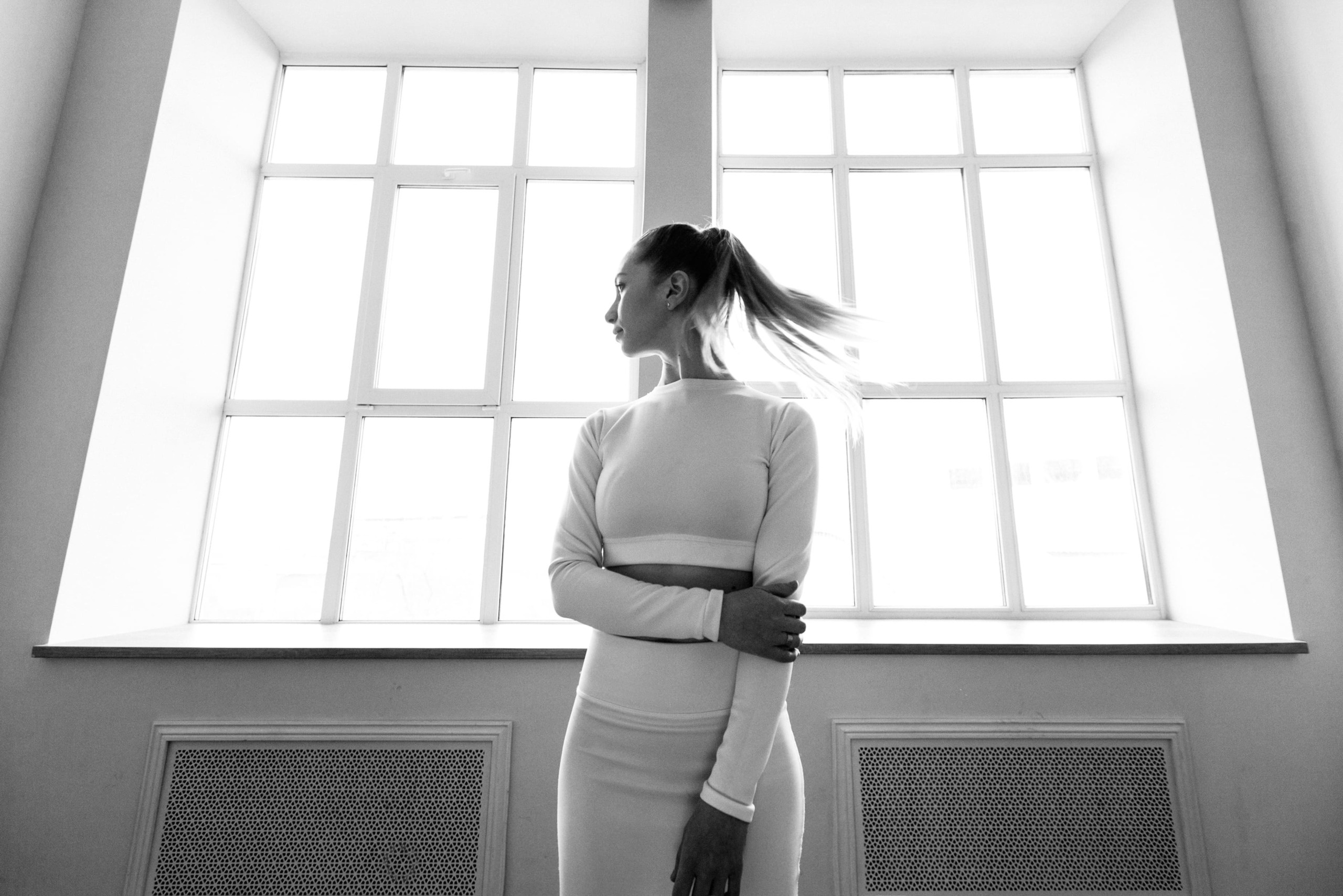 Frau posiert im Fotostudio vor zwei hohen, lichtdurchfluteten Fenstern.