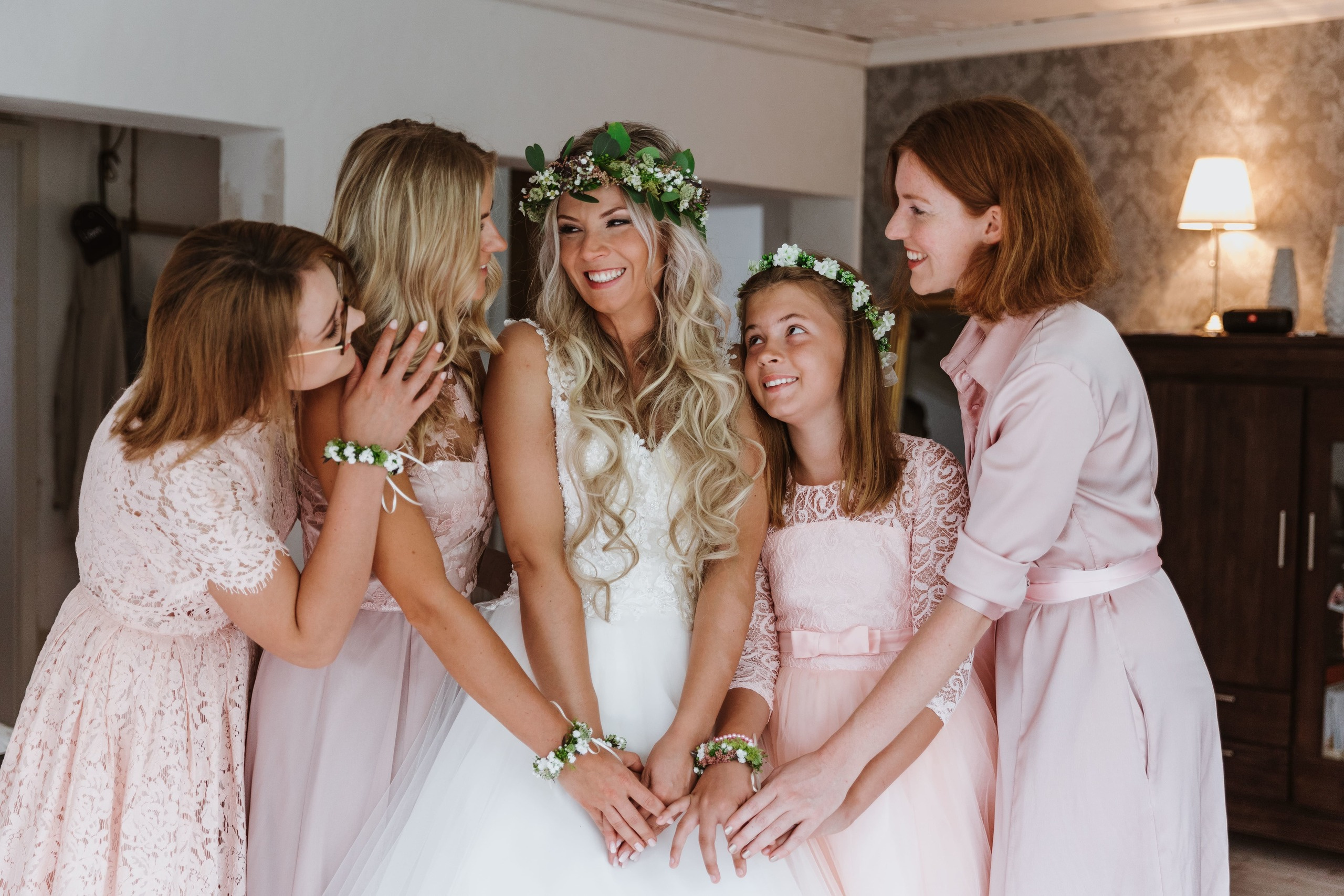 Brautjungfern umarmen die Braut und lachen gemeinsam.