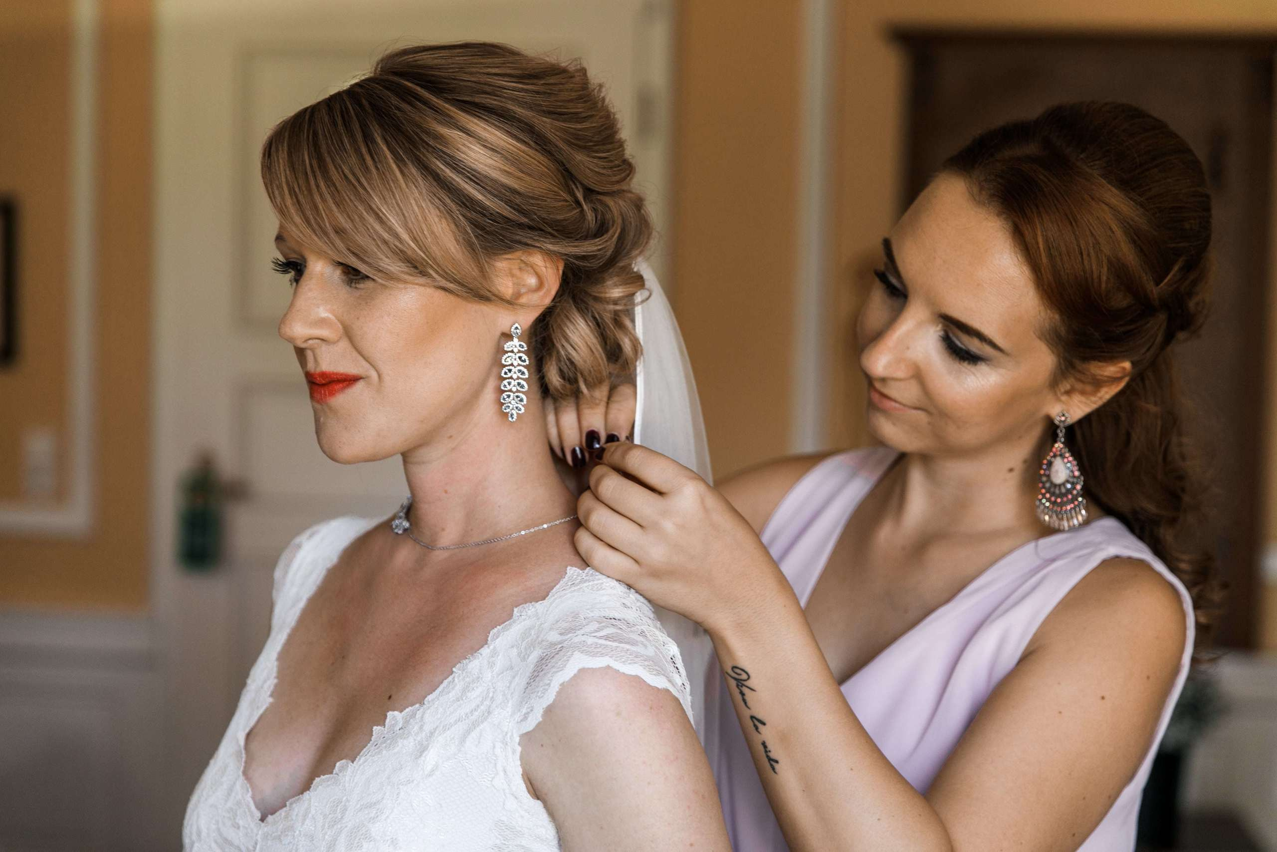 Die Brautjungfer hilft der Braut, ihren Schmuck anzulegen.