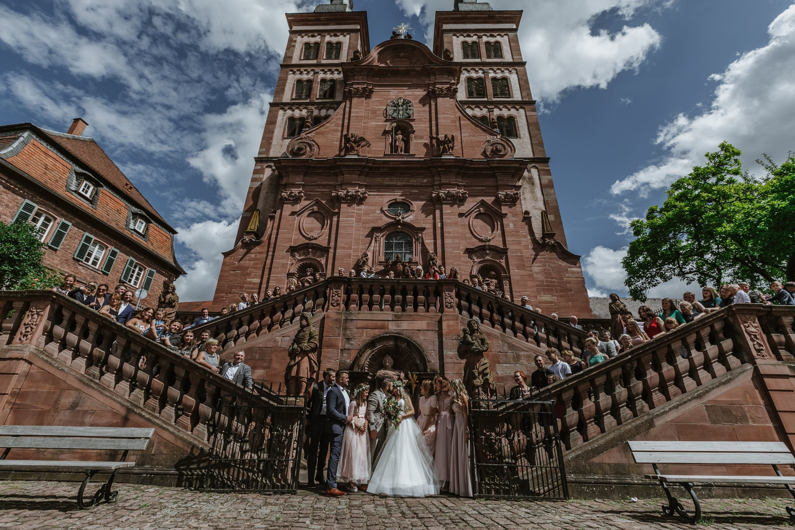 Gruppenfoto des Hochzeitspaars mit allen Gästen vor der Kirche.
