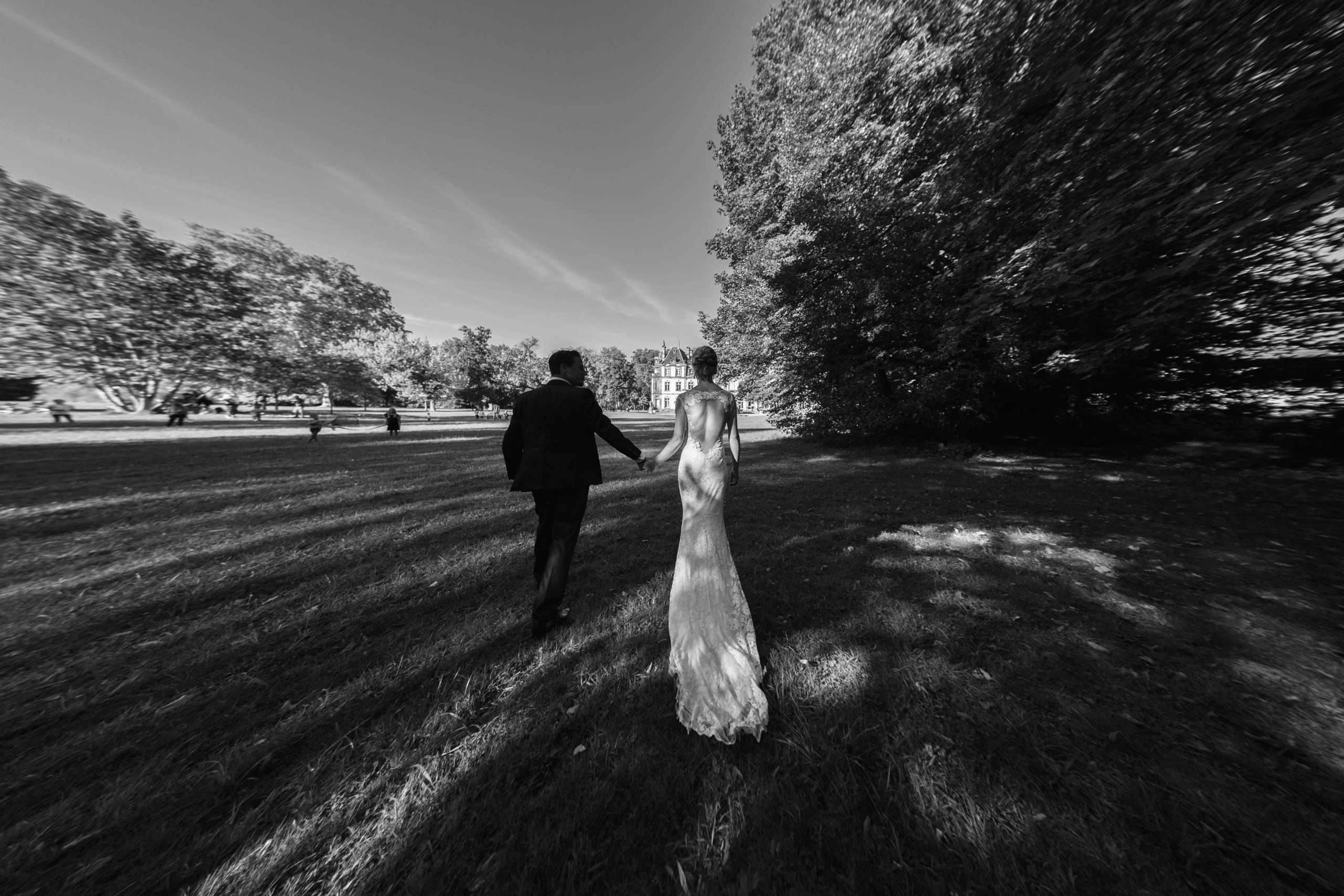 Brautpaar spaziert durch den Park zur Hochzeitslocation.