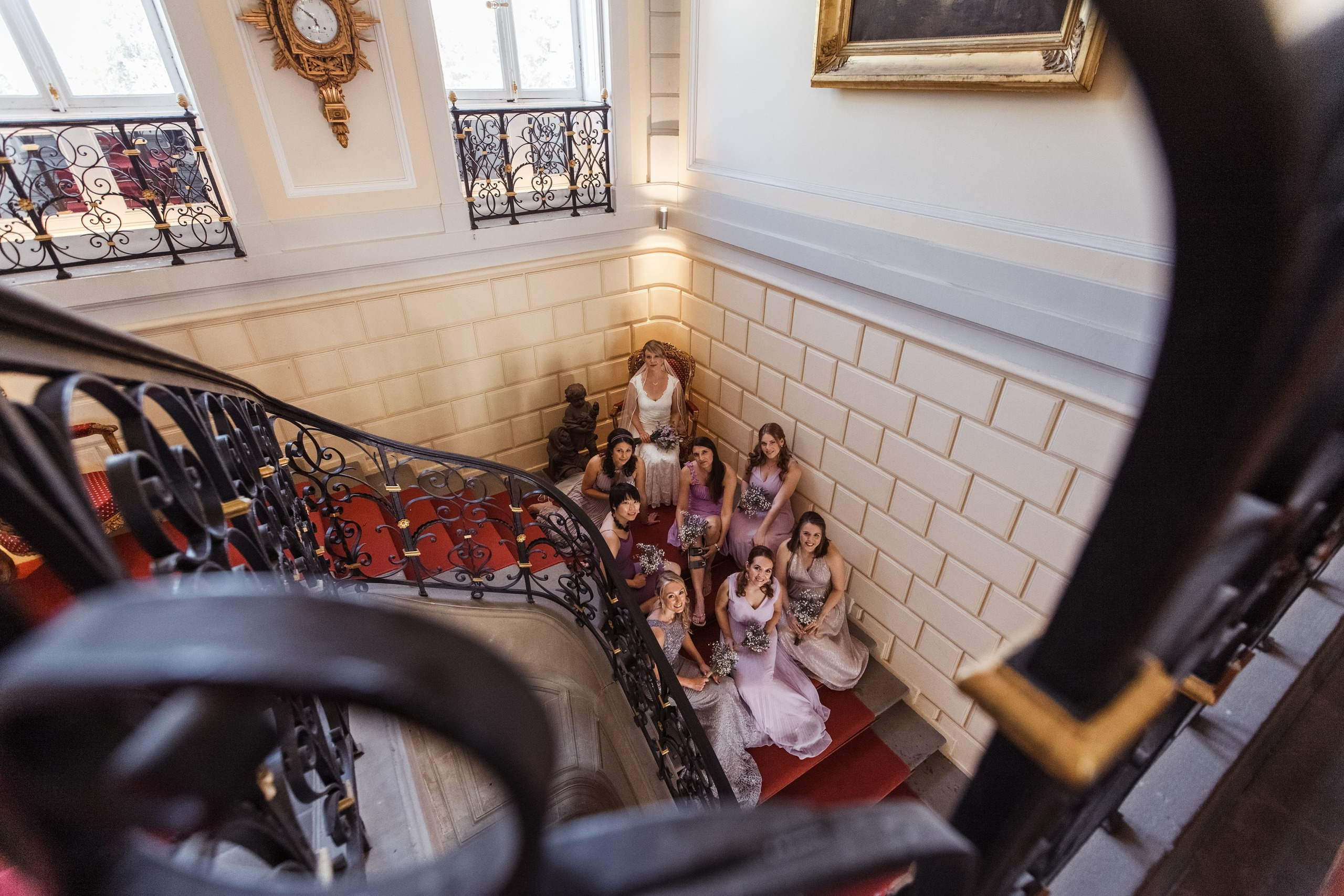 Die Braut sitzt in der Mitte, umgeben von ihren Brautjungfern auf der Treppe des Schlosses.