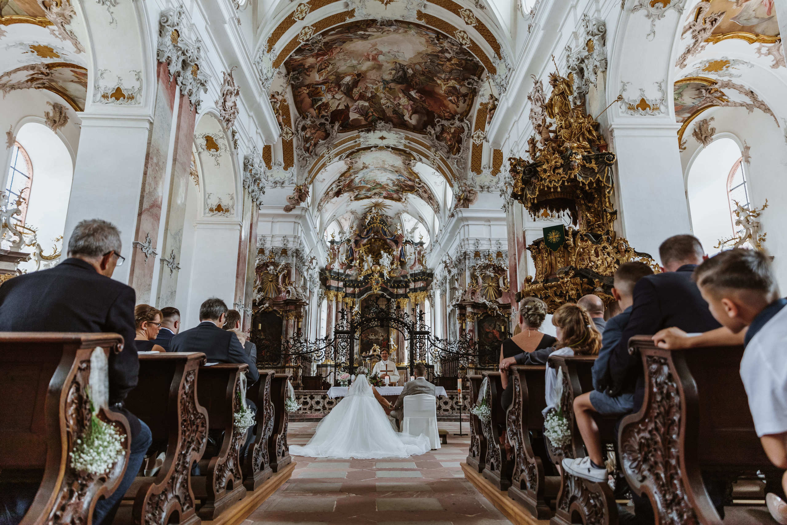 Gäste beobachten Braut und Bräutigam von hinten.