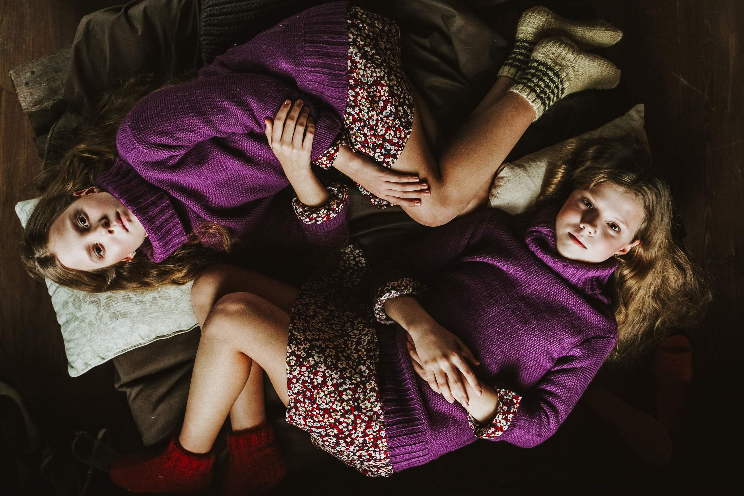 Zwillingsschwestern liegen zusammen und schauen während des winterlichen Fotoshootings im Studio in die Kamera.