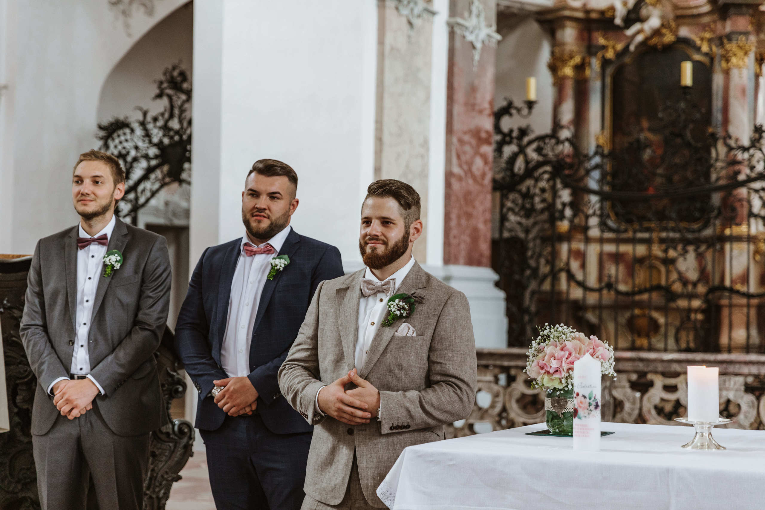 Der Bräutigam sieht seine Braut zum ersten Mal in der Kirche, ist nervös und lächelt.