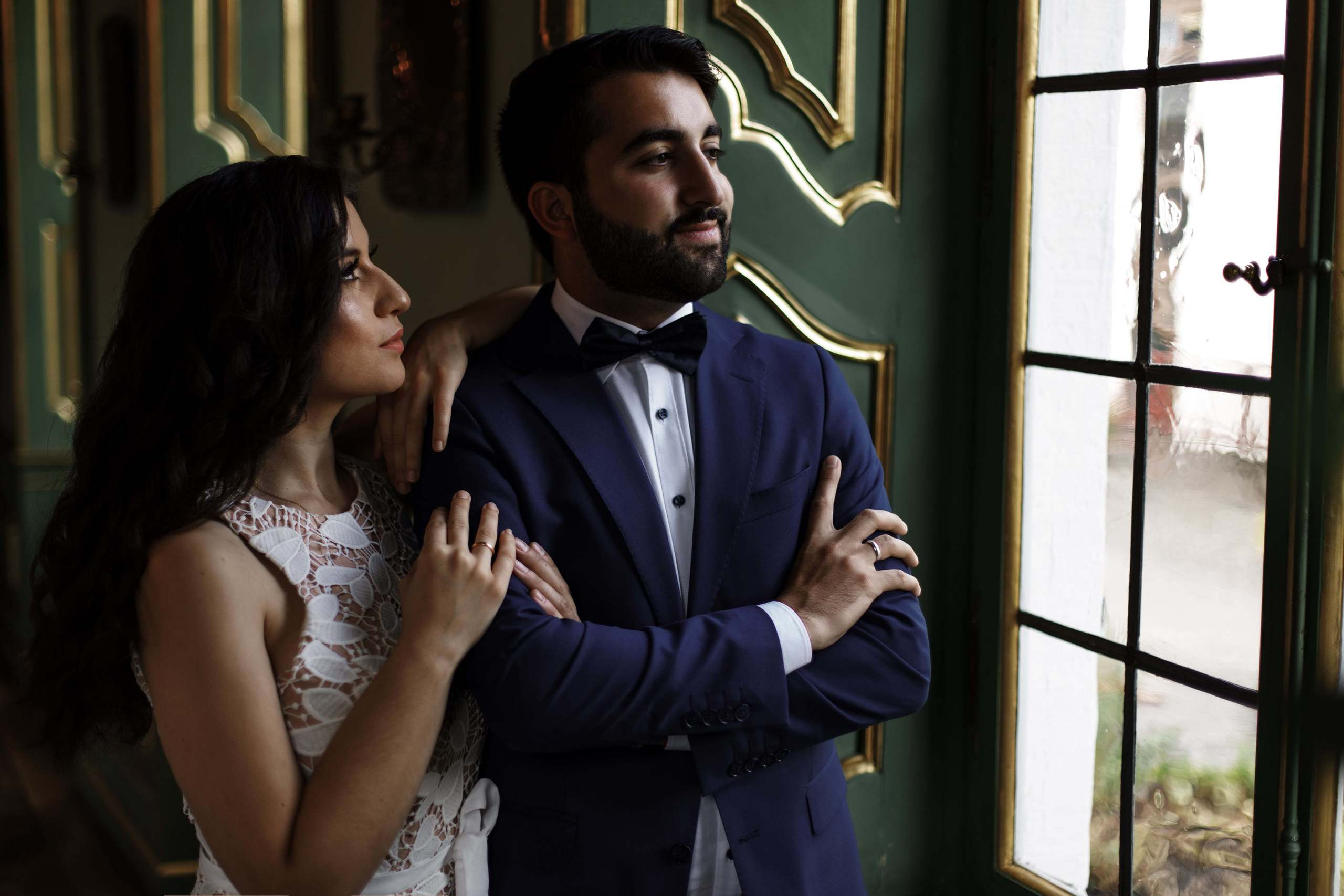 Die Braut schaut den Bräutigam an, während er aus dem Fenster blickt.