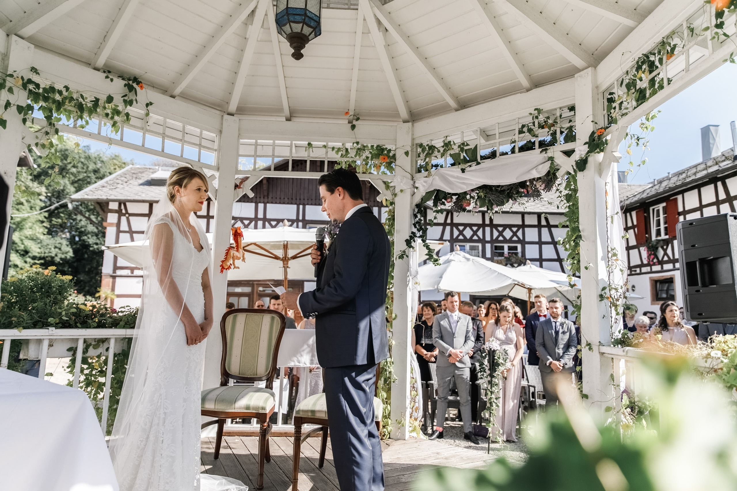 Bräutigam und Braut lesen ihre Eheversprechen im Pavillon im Schlossgarten von Château de Pourtalès.