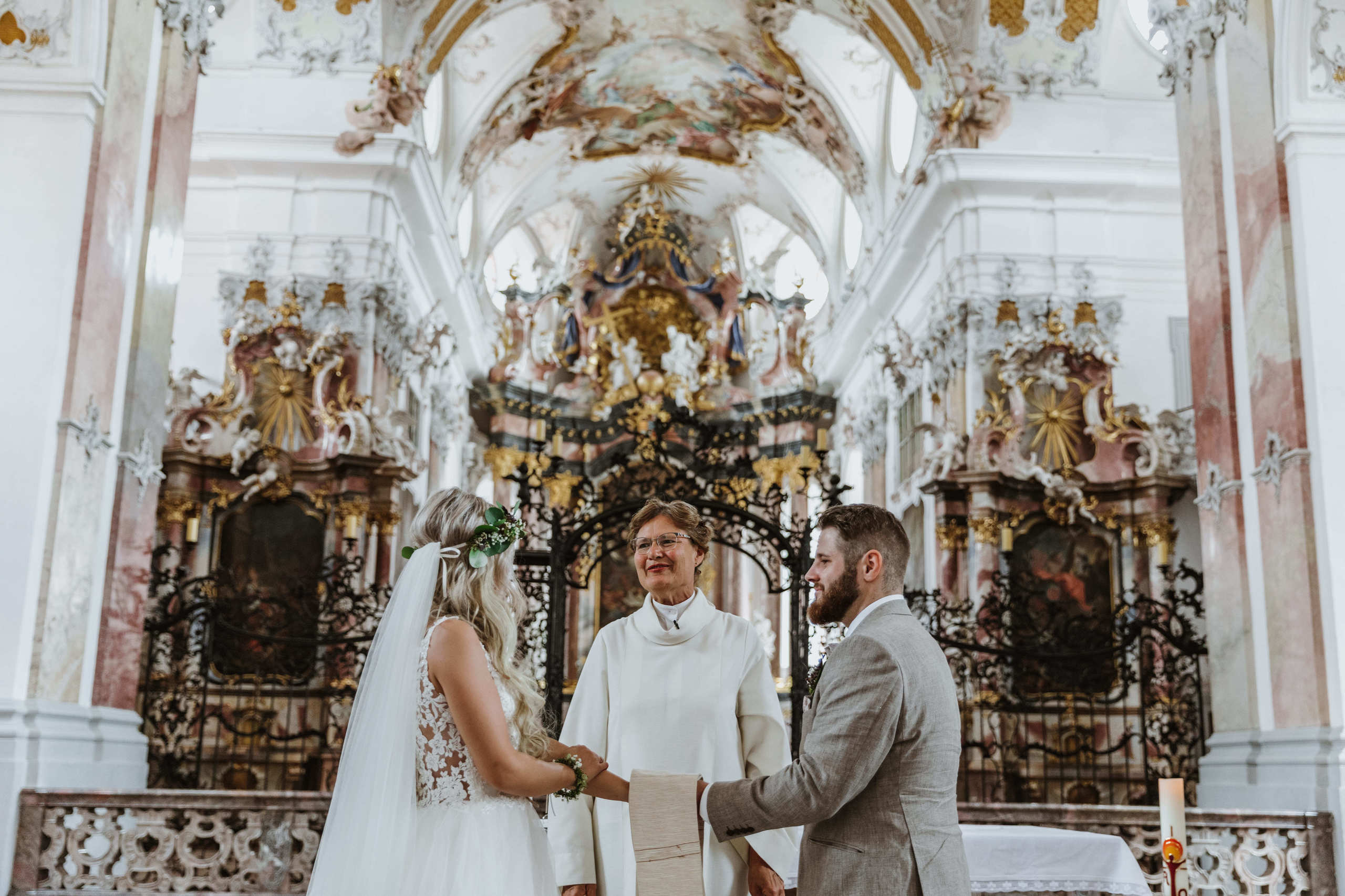 Der Bräutigam und die Braut schauen sich verliebt vor dem Altar an.