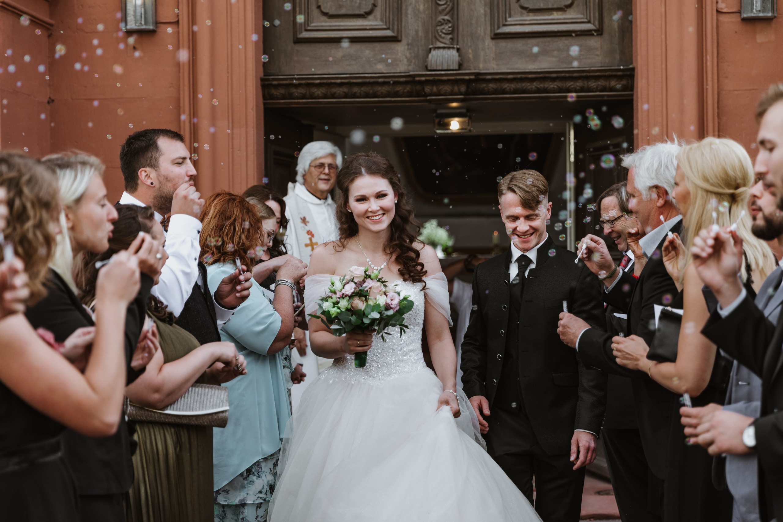 Bräutigam und Braut verlassen die Kirche und werden von den Gästen herzlich empfangen.