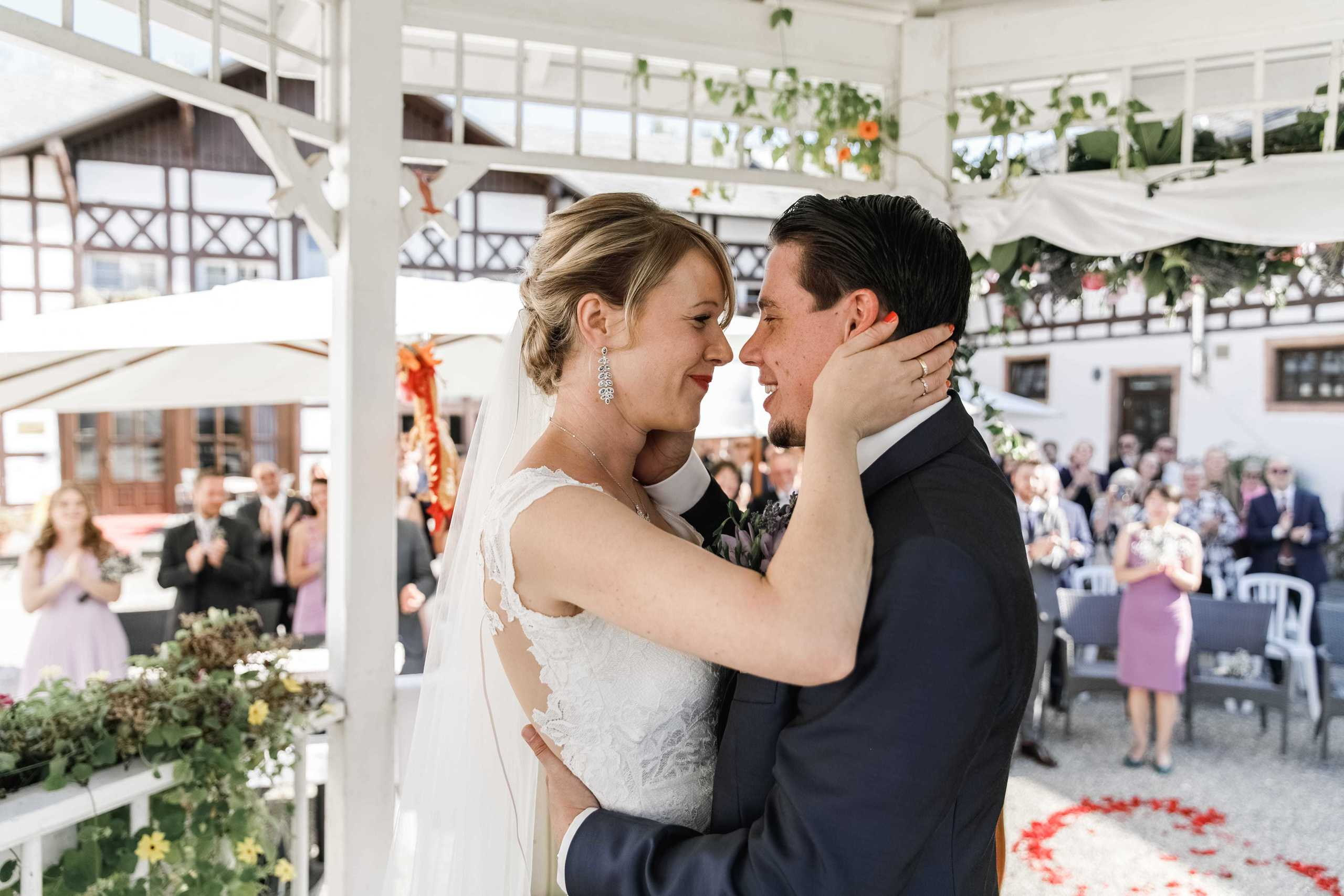 Bräutigam und Braut geben sich den ersten Hochzeitskuss bei der Zeremonie.