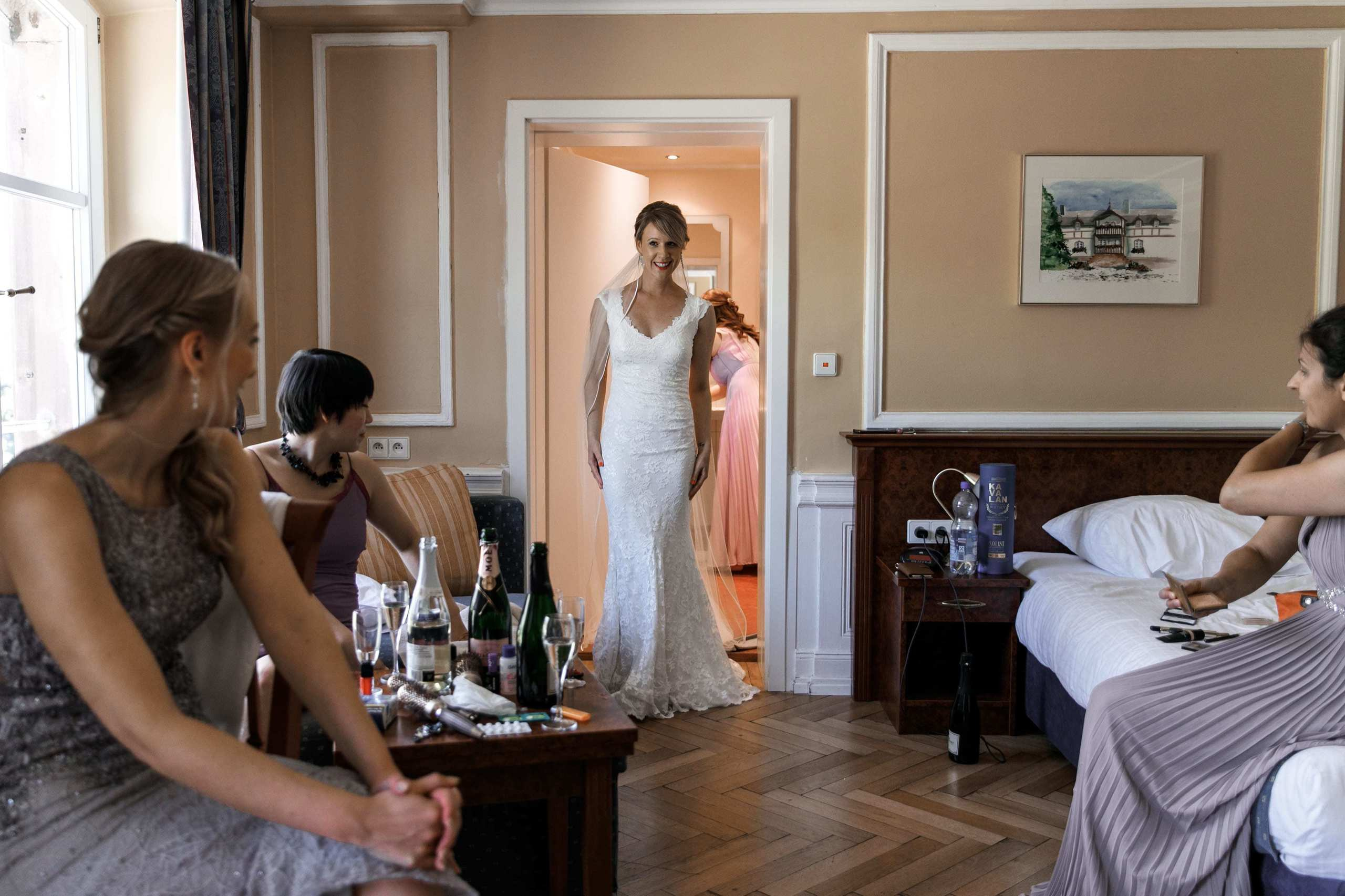 Brautjungfern beobachten, wie die Braut in ihrem Hochzeitskleid aus der Umkleide kommt.