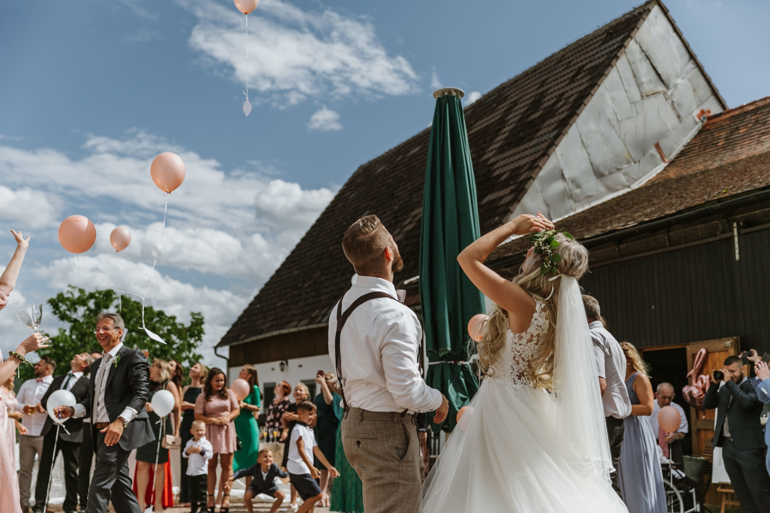 Das Brautpaar schaut den Hochzeitsballons hinterher, die in die Ferne fliegen.