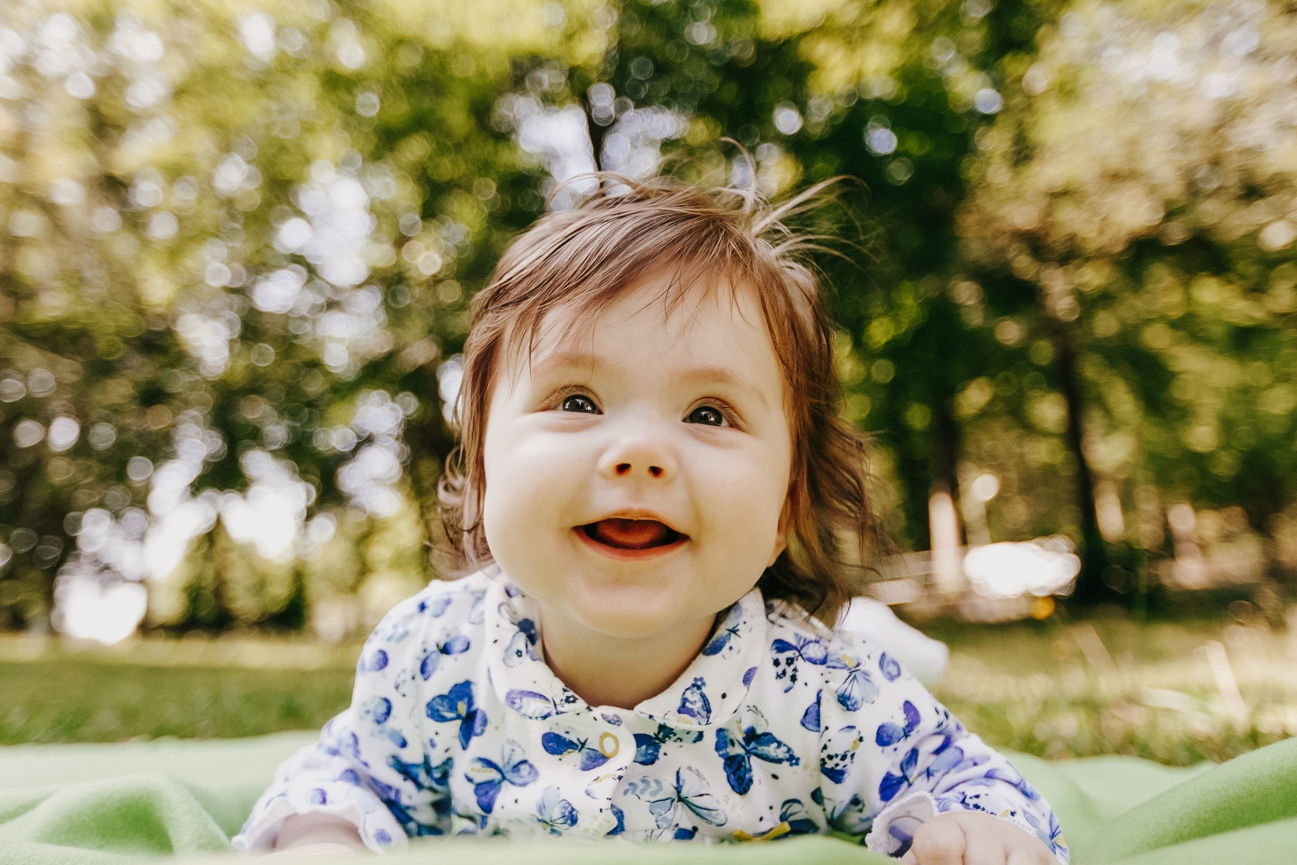 Kleines Mädchen liegt auf der Wiese und lächelt.