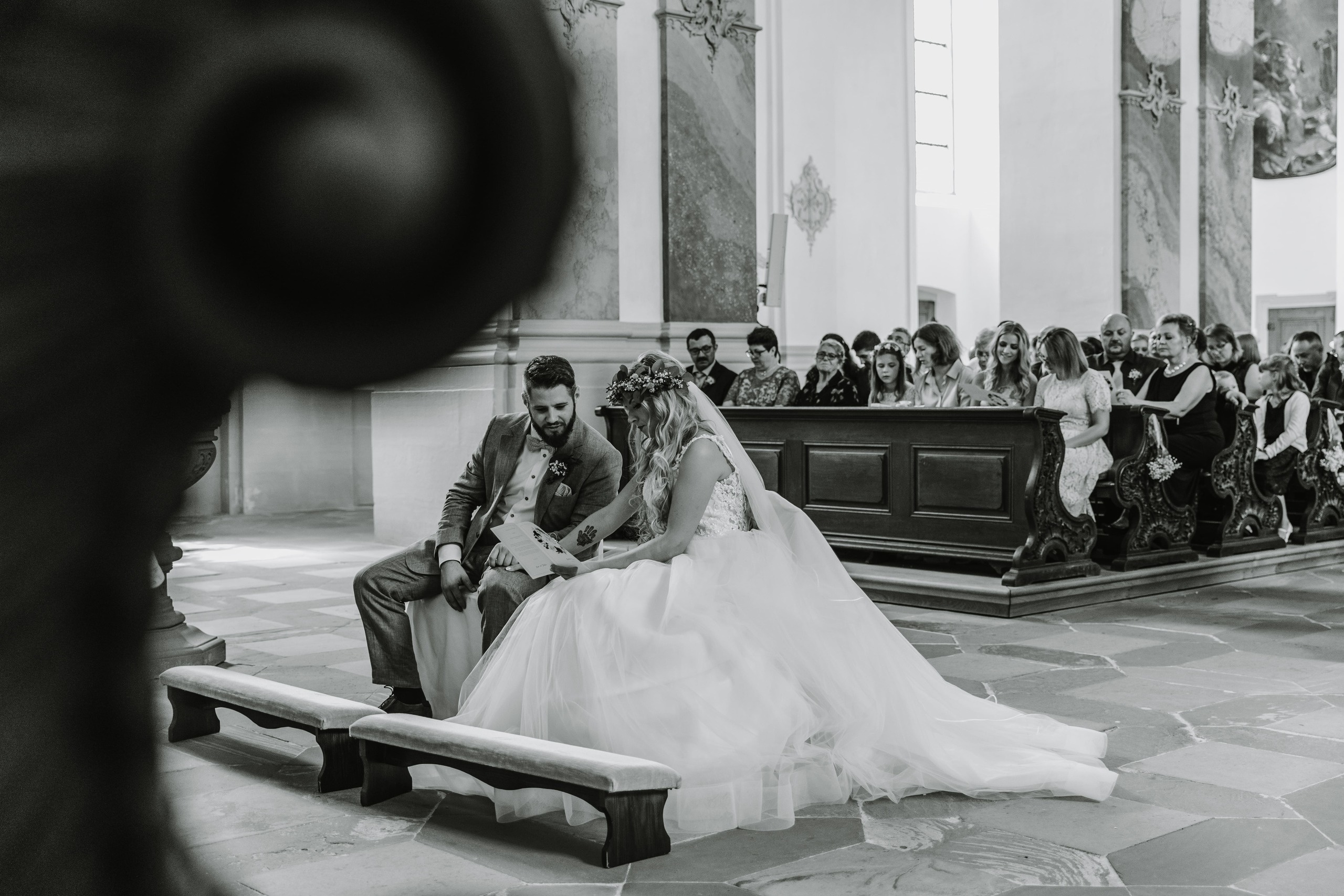 Braut und Bräutigam schauen in das Kirchenheft und singen mit den Gästen.