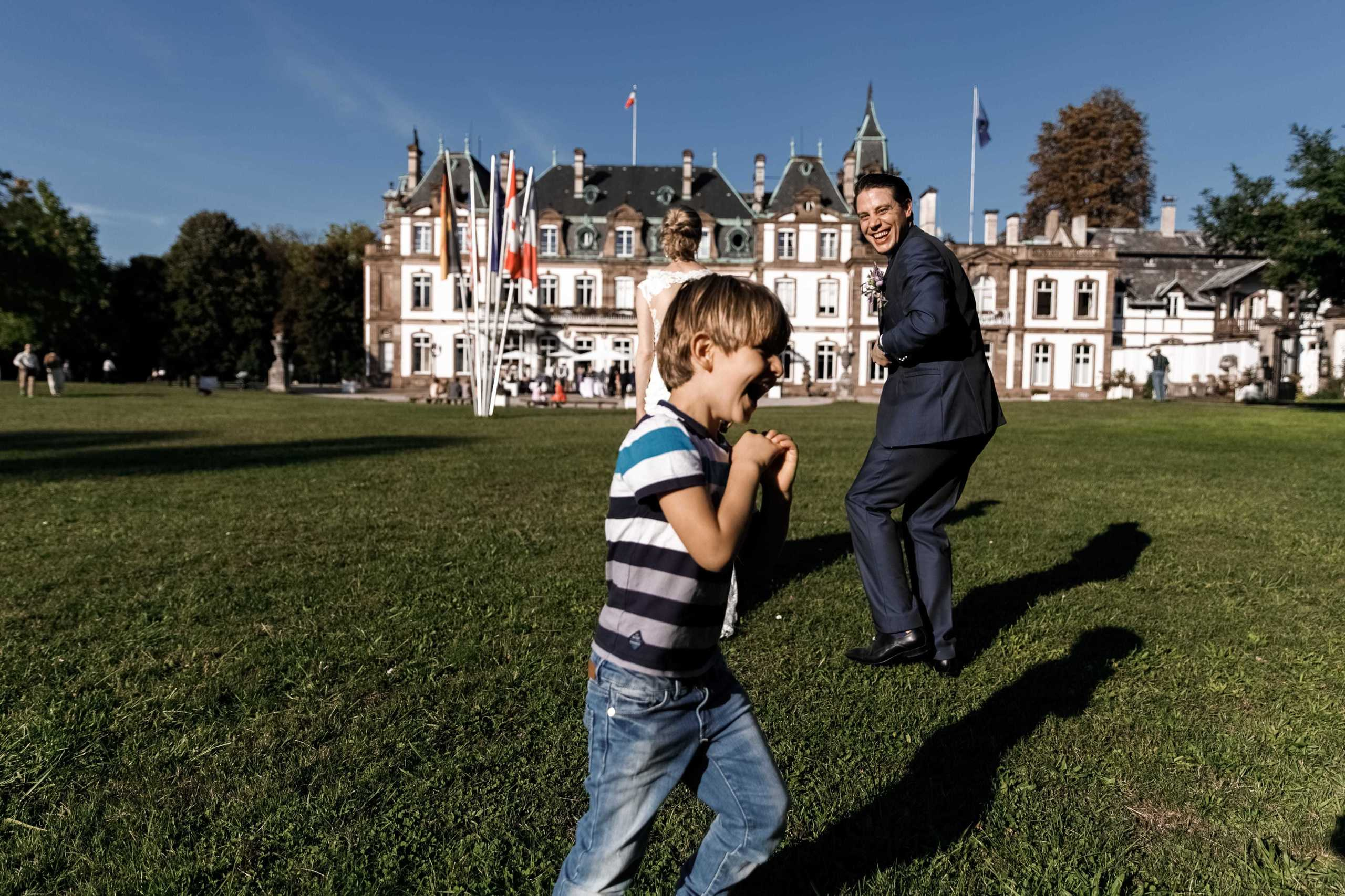 Ein Junge läuft lachend an dem Brautpaar vorbei.