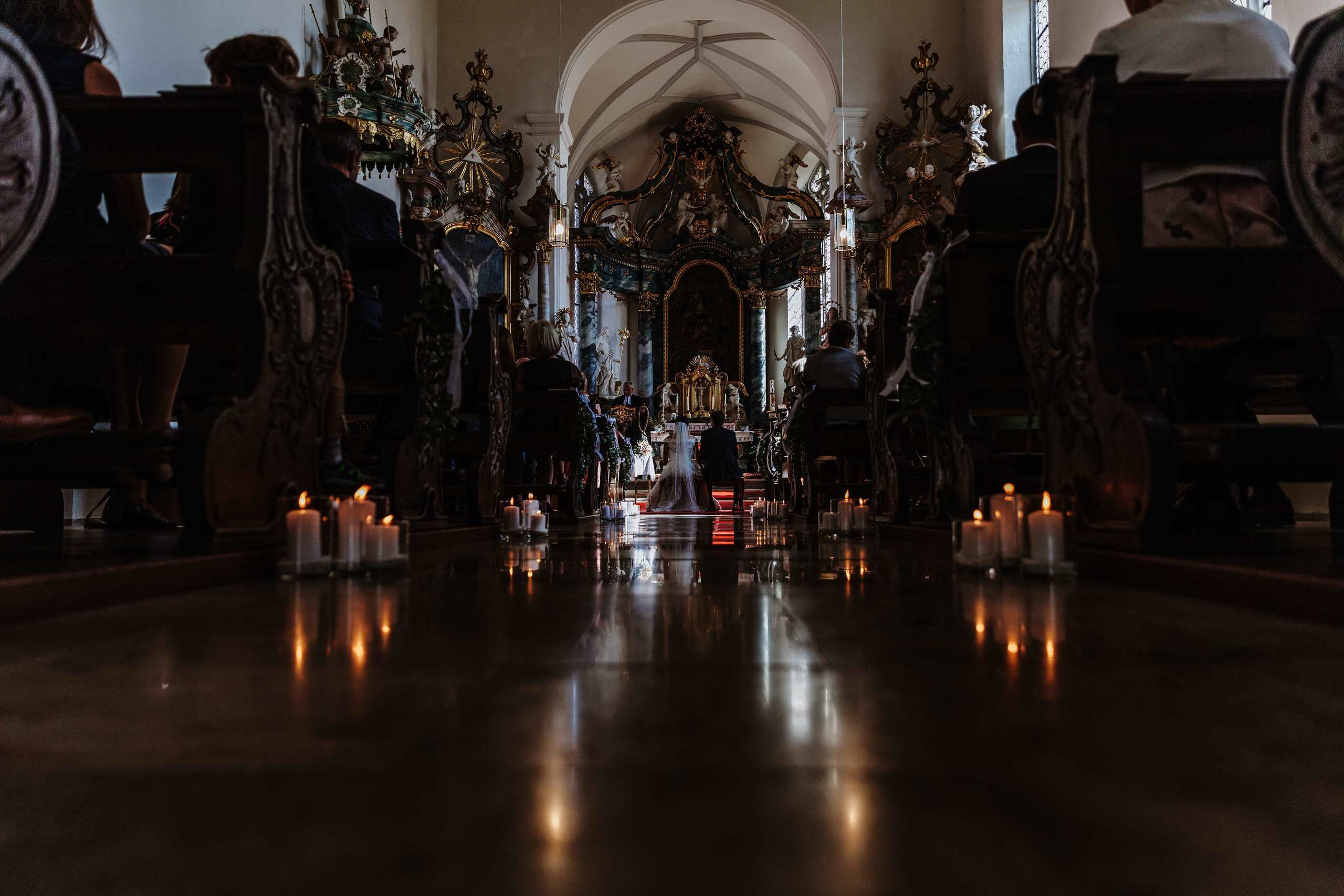 Kerzen auf dem Boden in einer eleganten Kirche während der Hochzeitszeremonie.