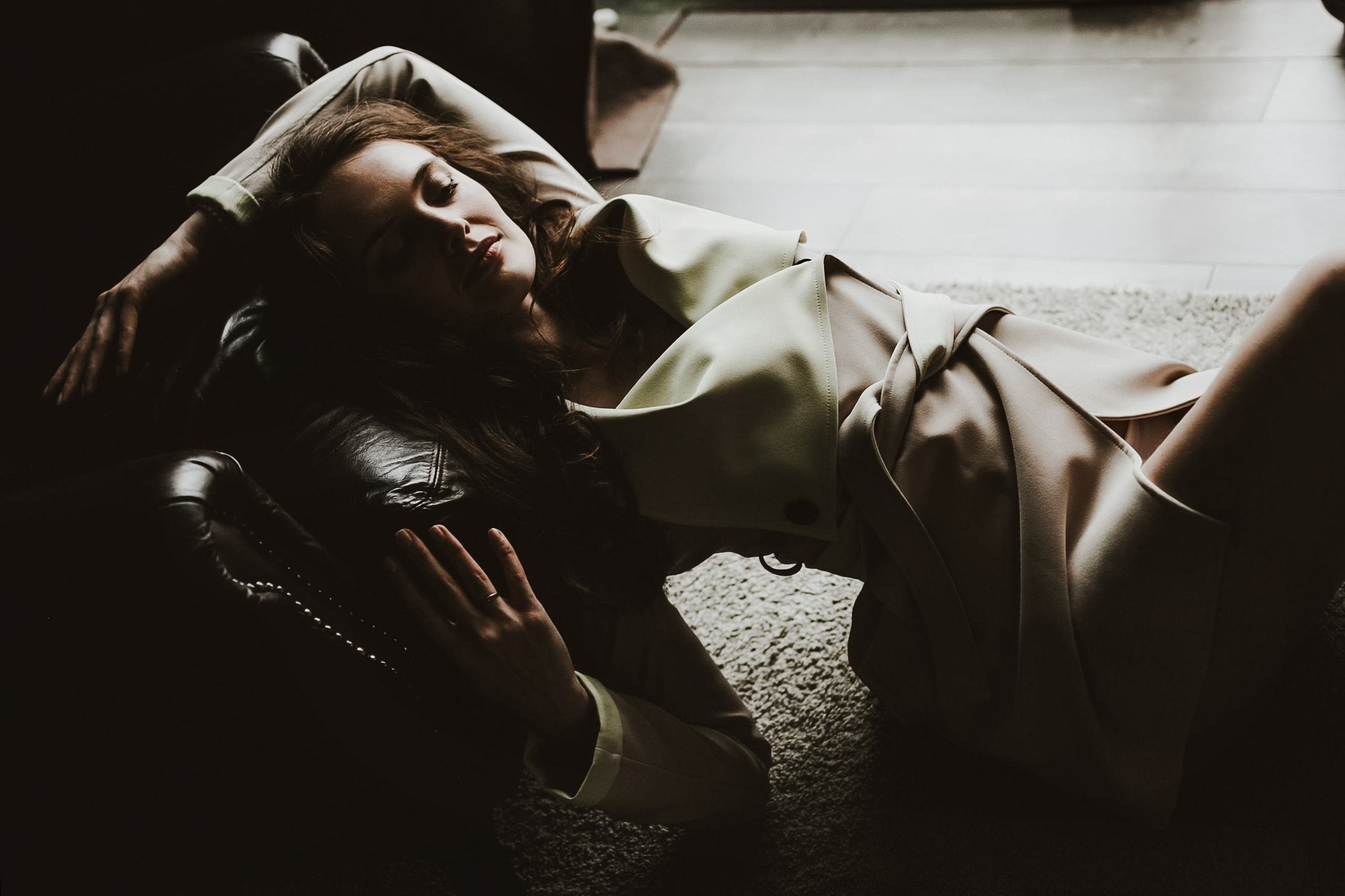 Junges Mädchen liegt entspannt am Boden neben einem großen Fenster im  Fotostudio.