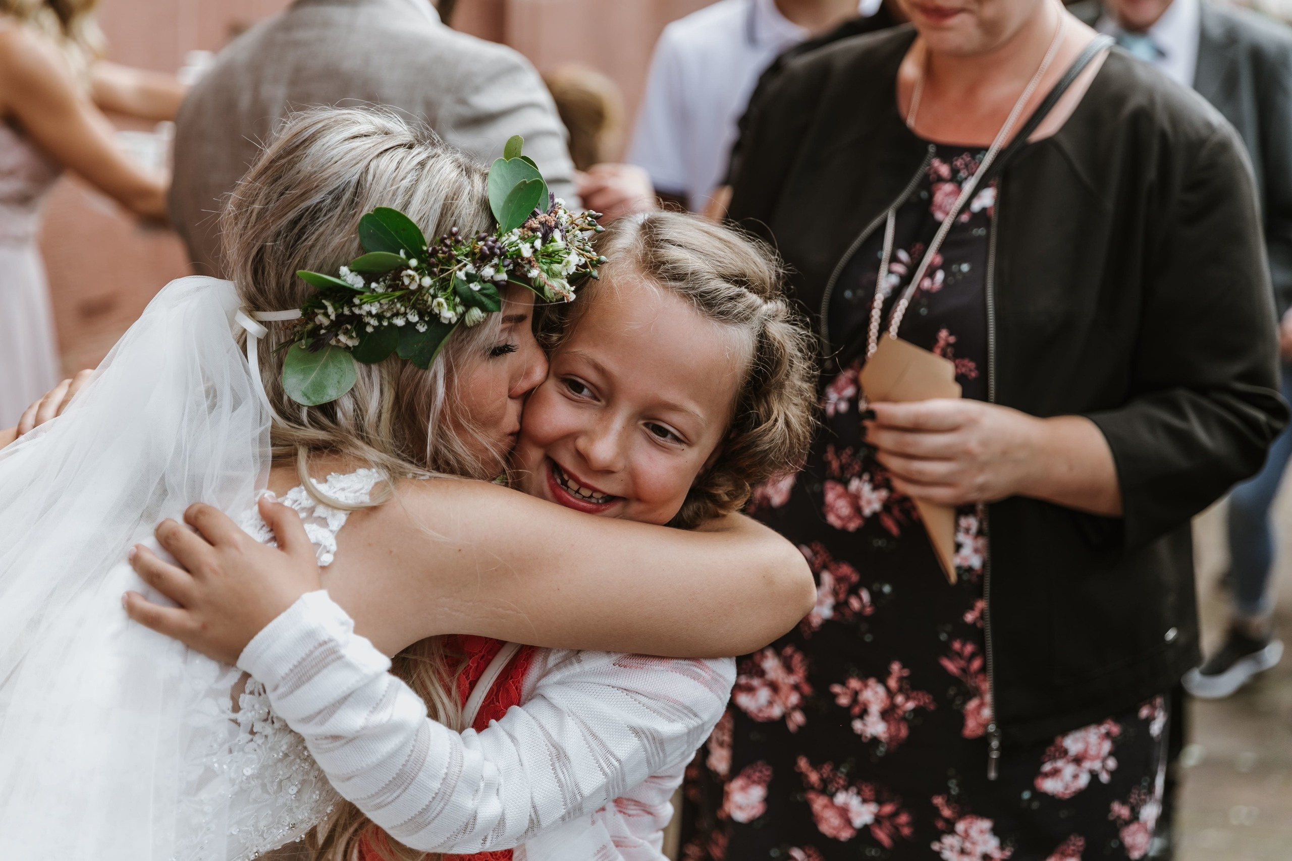 Die Braut küsst das Mädchen auf die Wange und umarmt sie herzlich.