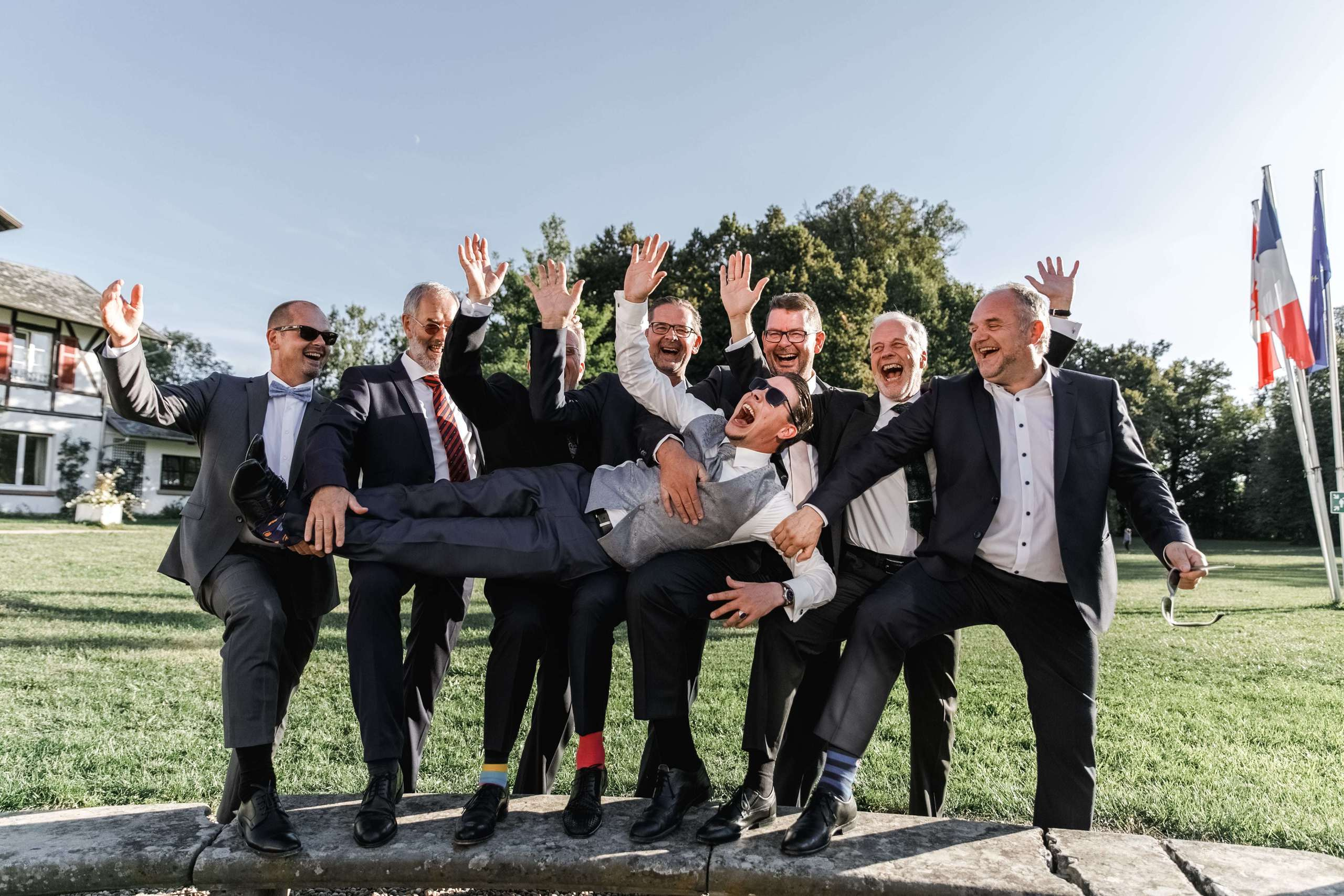 Die Groomsmen heben den Bräutigam hoch – fröhlicher Moment während der Hochzeit.