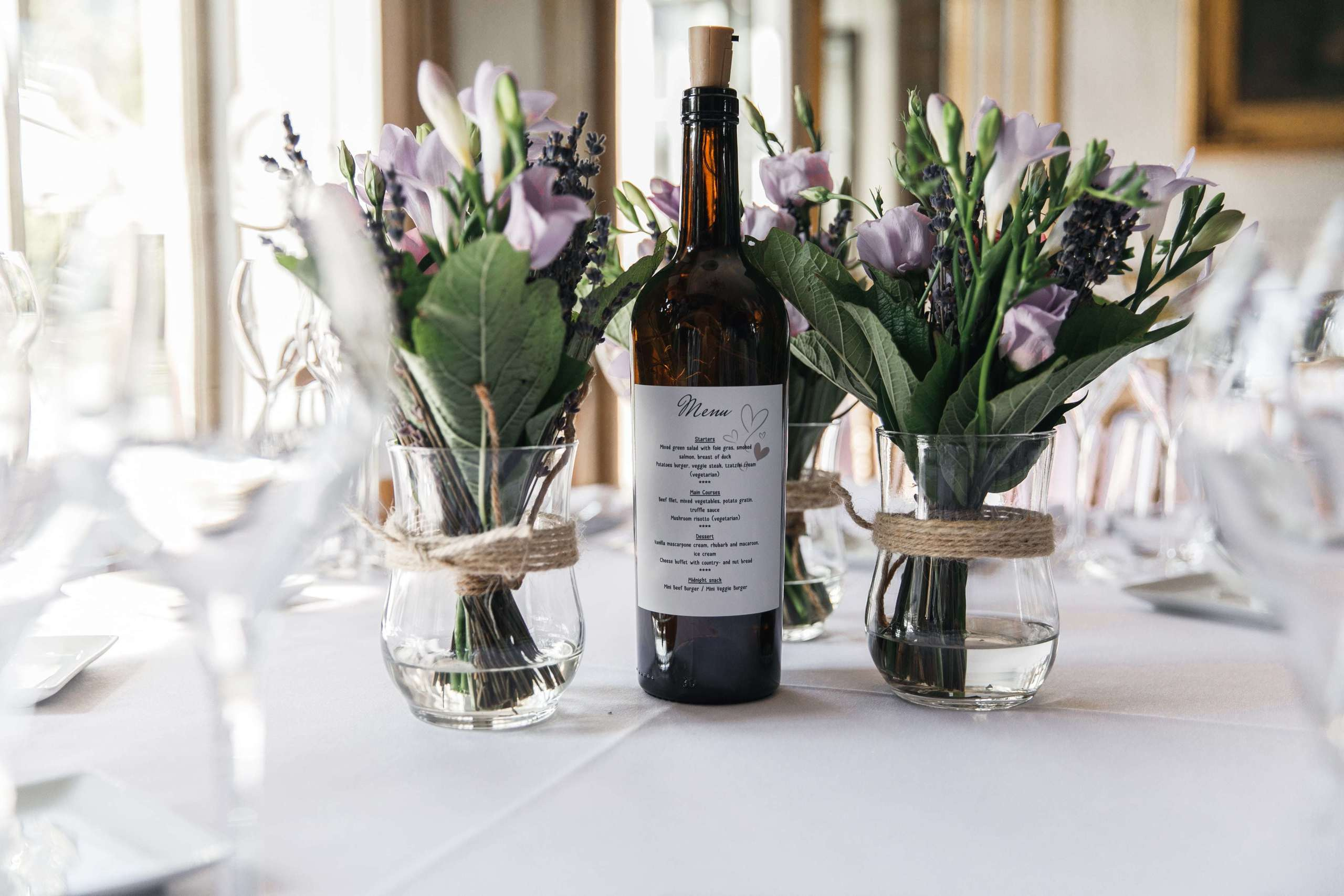 Tischdekoration mit frischem Lavendel, Weinflasche und Menü.