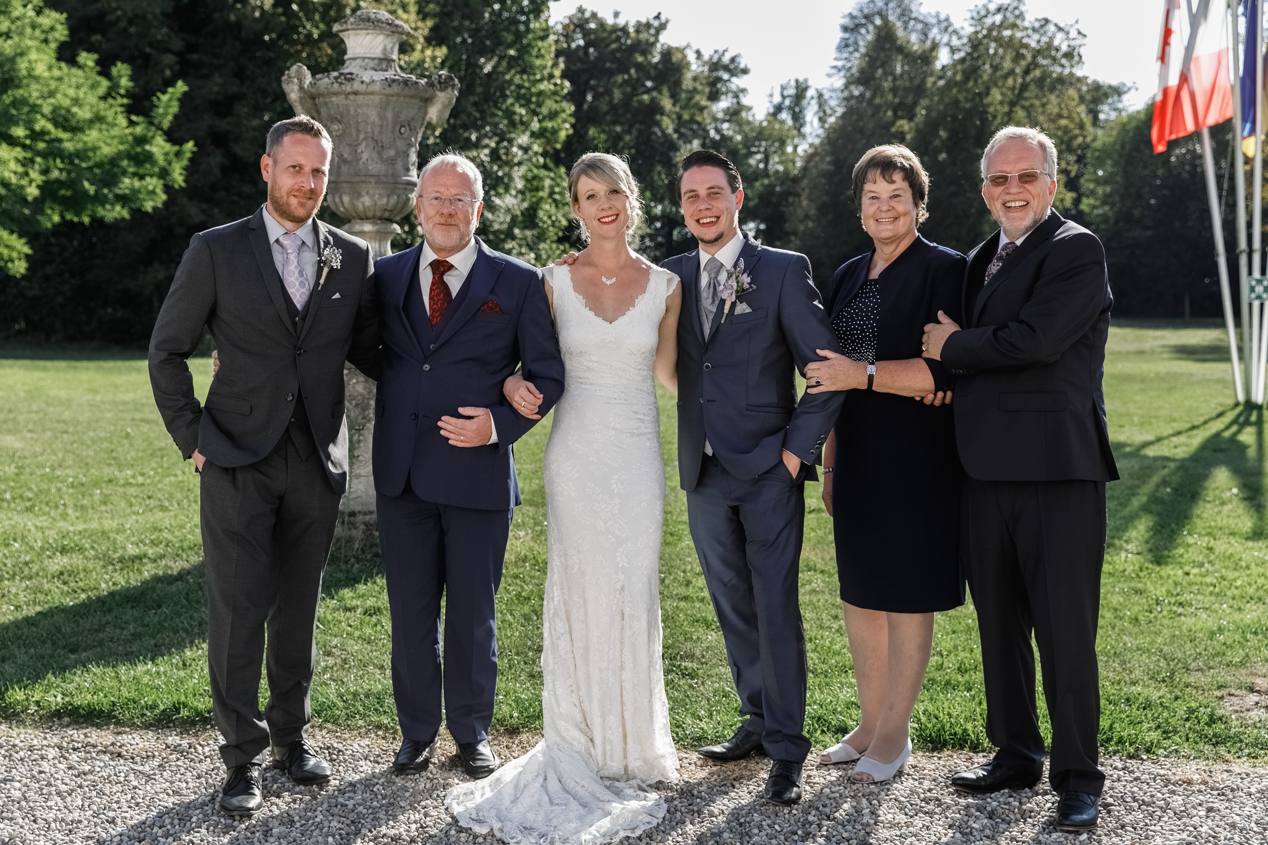 Hochzeitspaar mit Eltern blickt lächelnd in die Kamera.