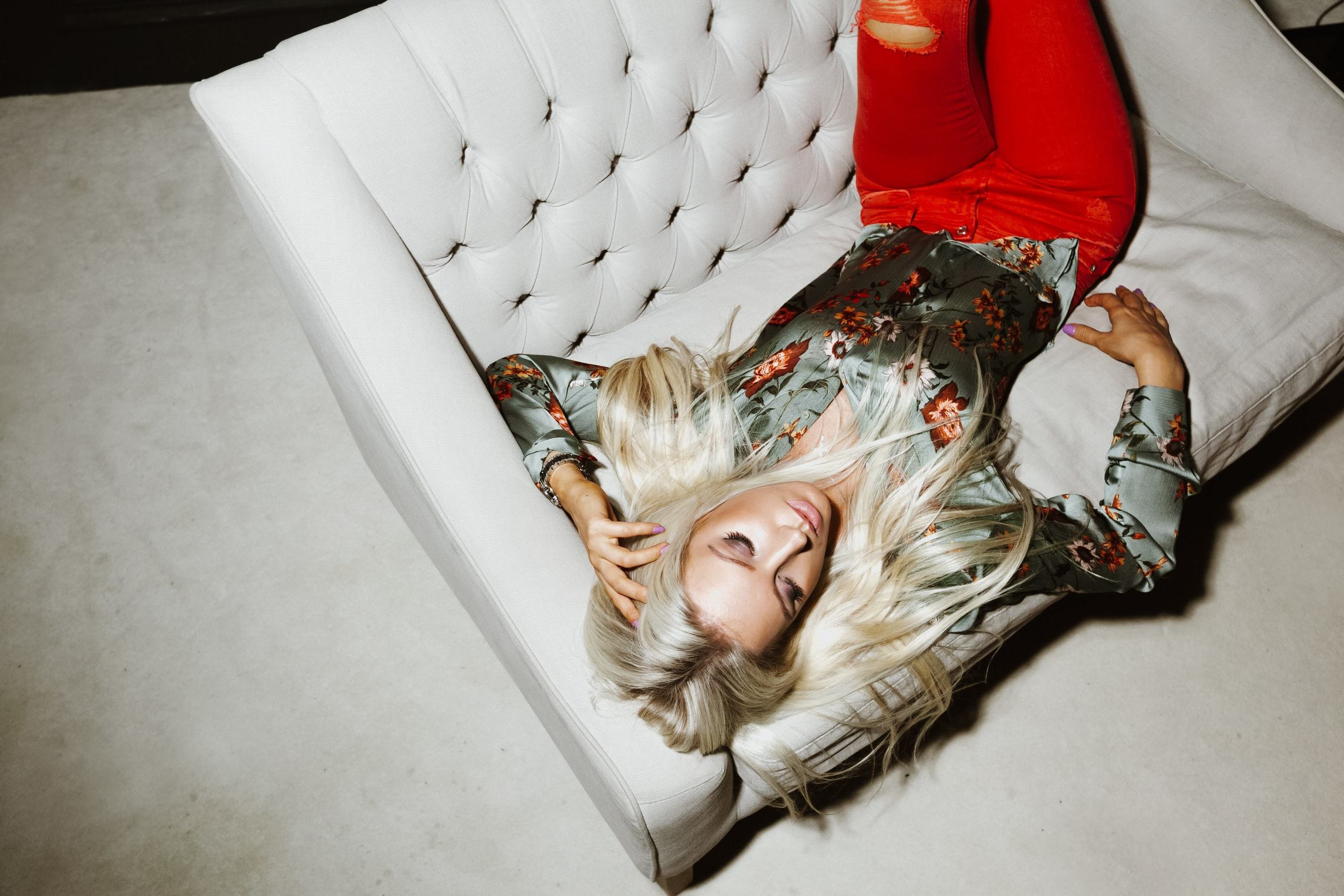 Frau liegt entspannt auf einem stilvollen Sofa im Fotostudio – Porträtmoment.