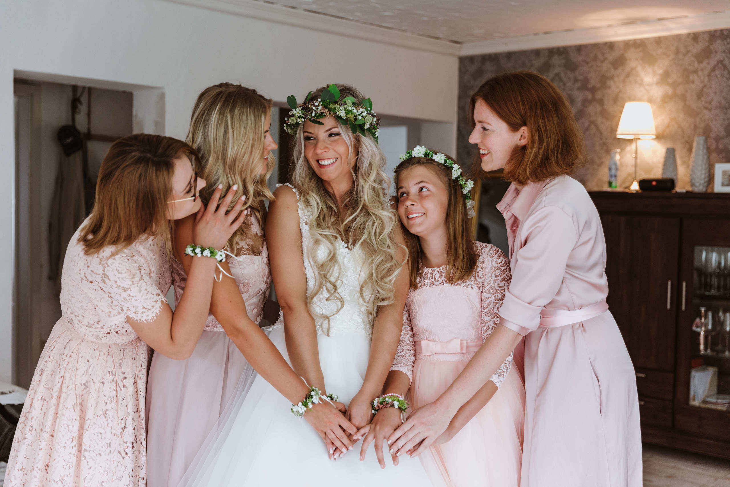 Brautjungfern umarmen die Braut und lachen gemeinsam.