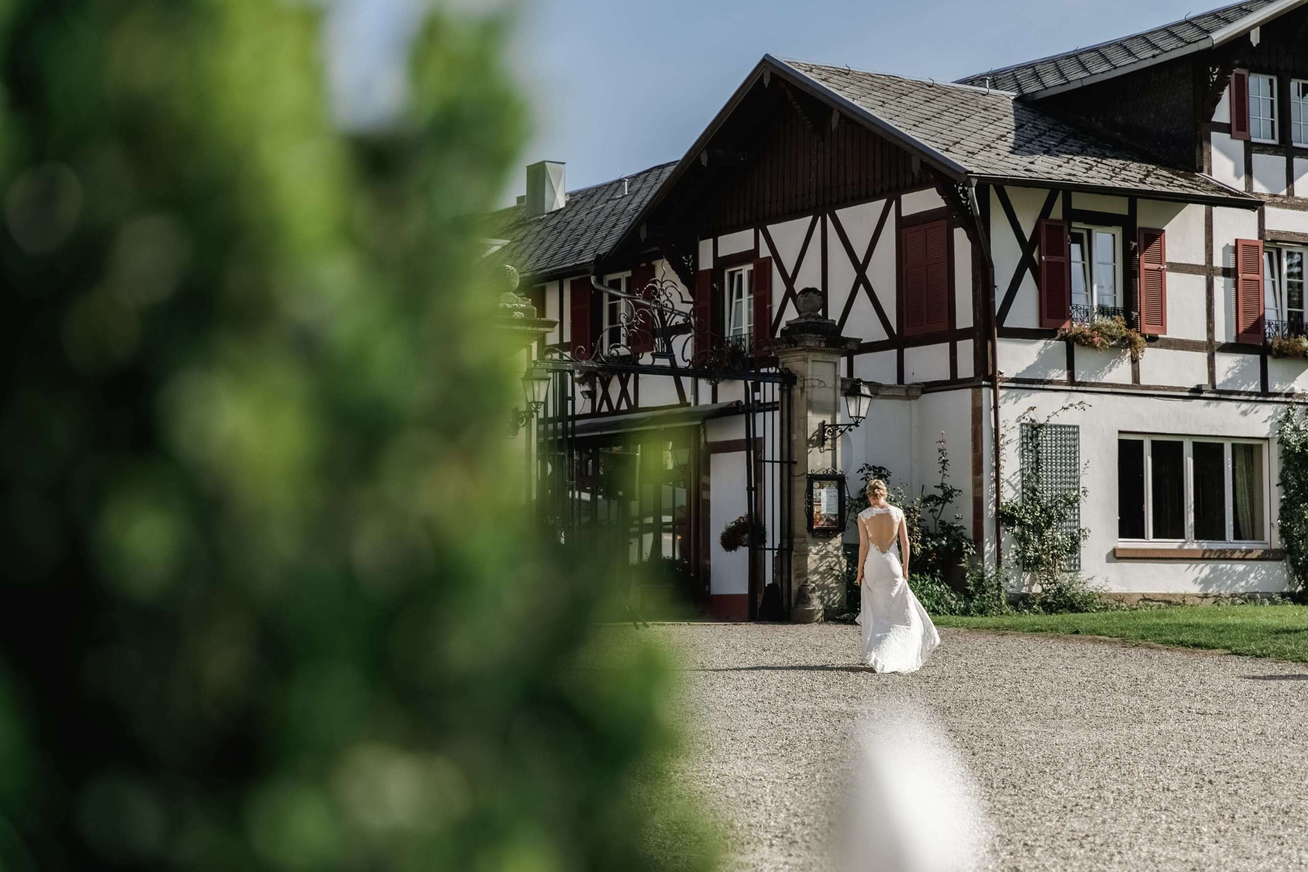 Braut in schönem Hochzeitskleid geht zum Schloss Château de Pourtalès.