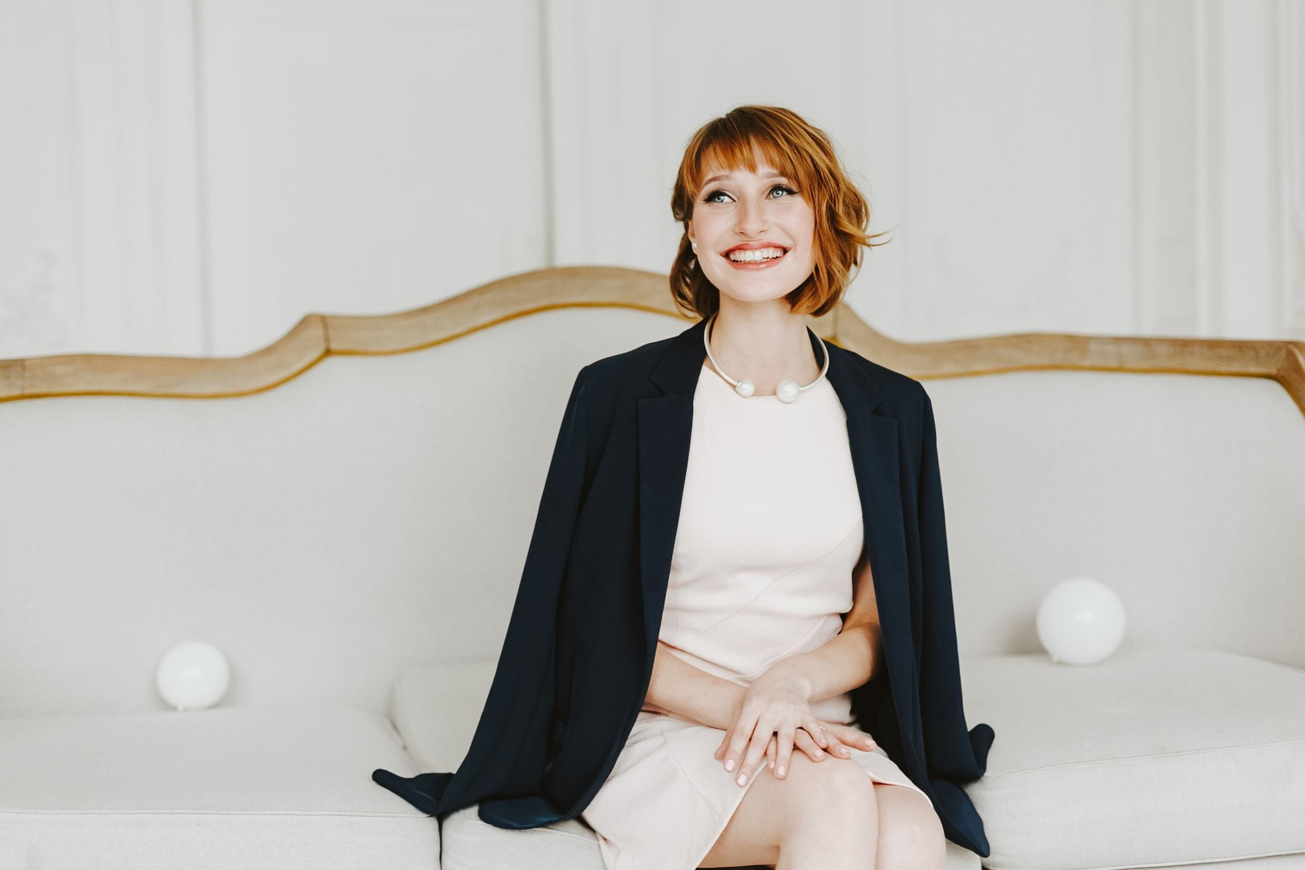 Frau im romantischen Look sitzt entspannt auf einem Vintage-Sofa während eines stilvollen Fotoshootings