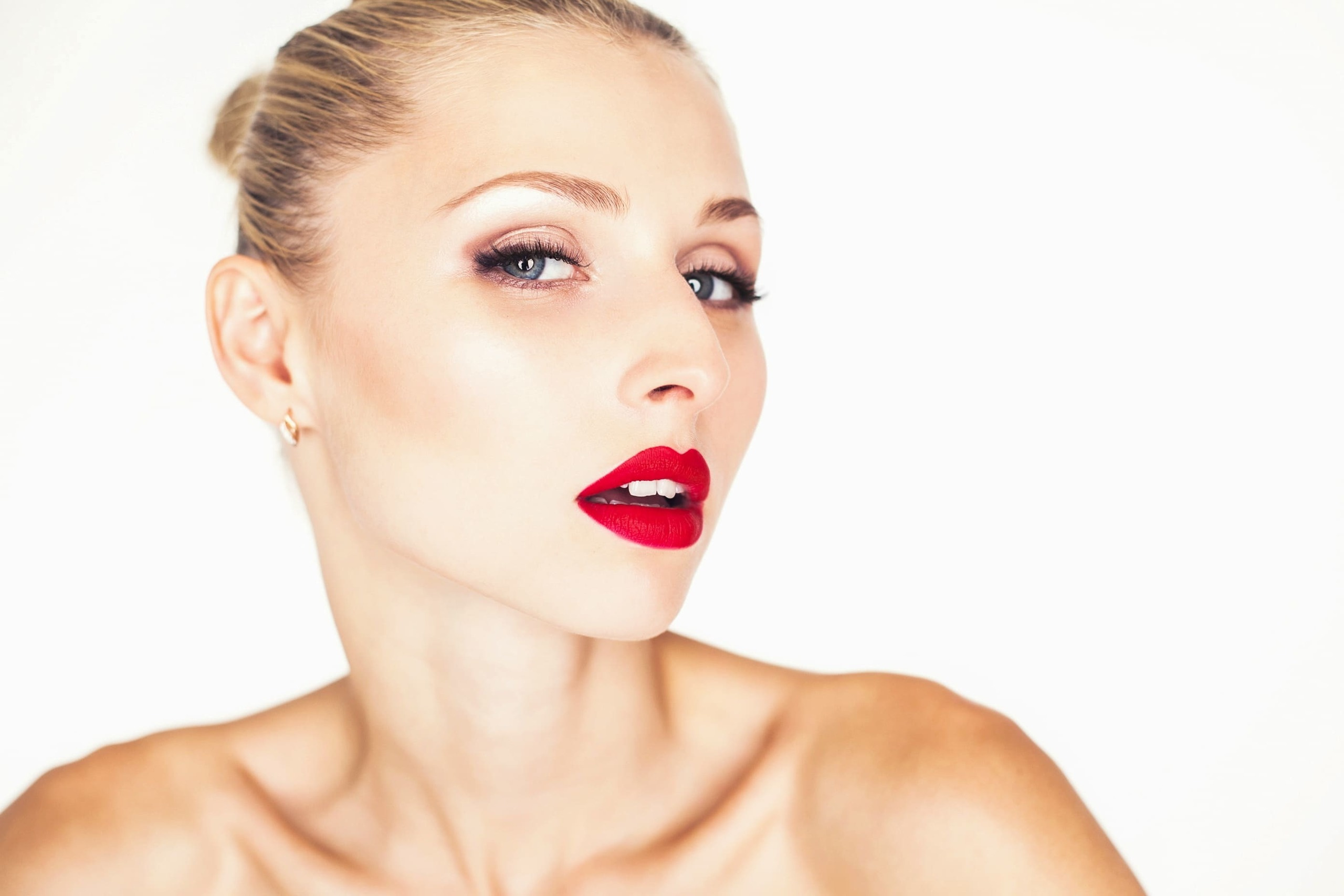 Elegante Frau präsentiert während eines Beauty-Werbe-Fotoshootings einen leuchtend roten Lippenstift in Nahaufnahme.