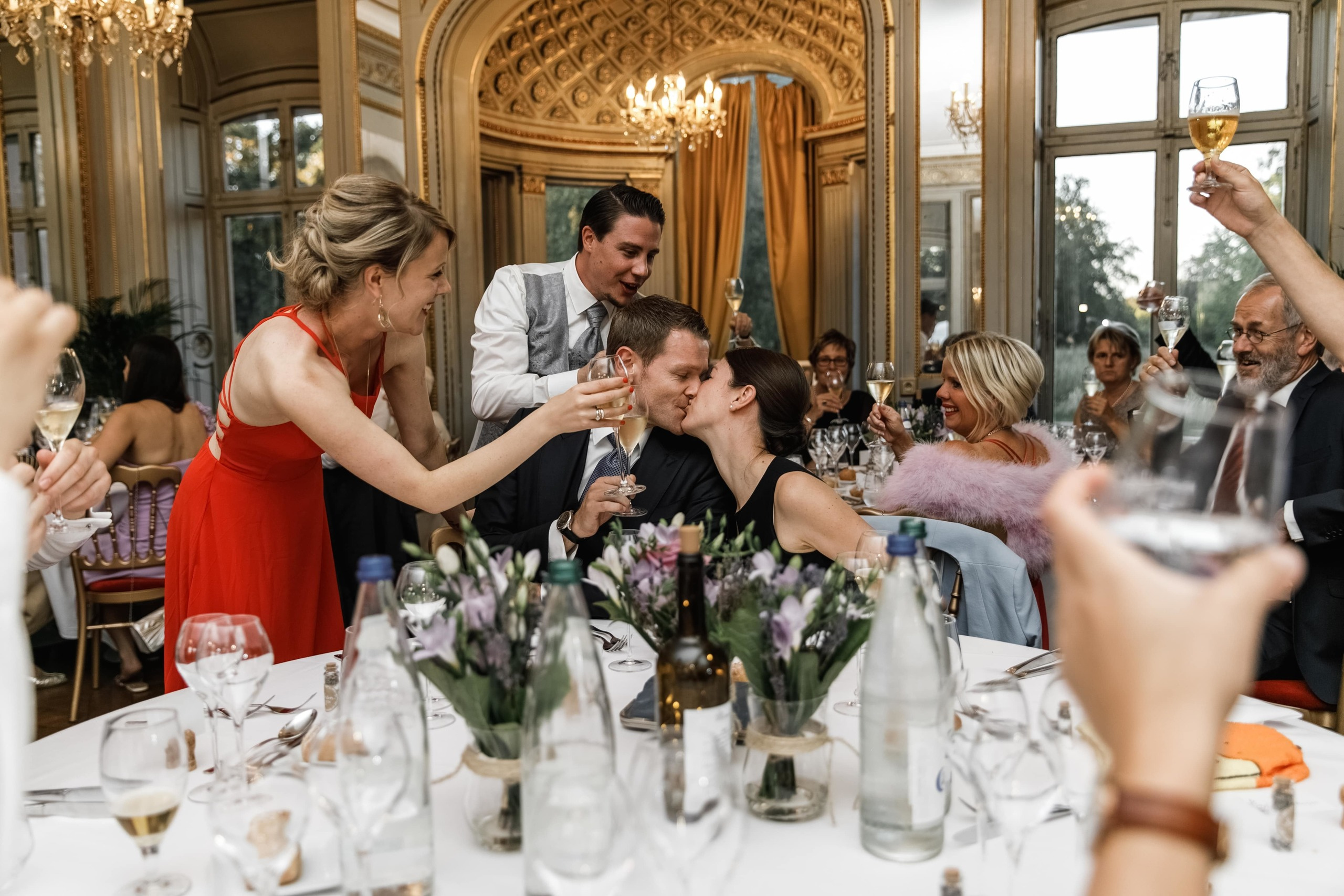 Bräutigam und Braut gratulieren einem anderen Paar, das sich küsst.