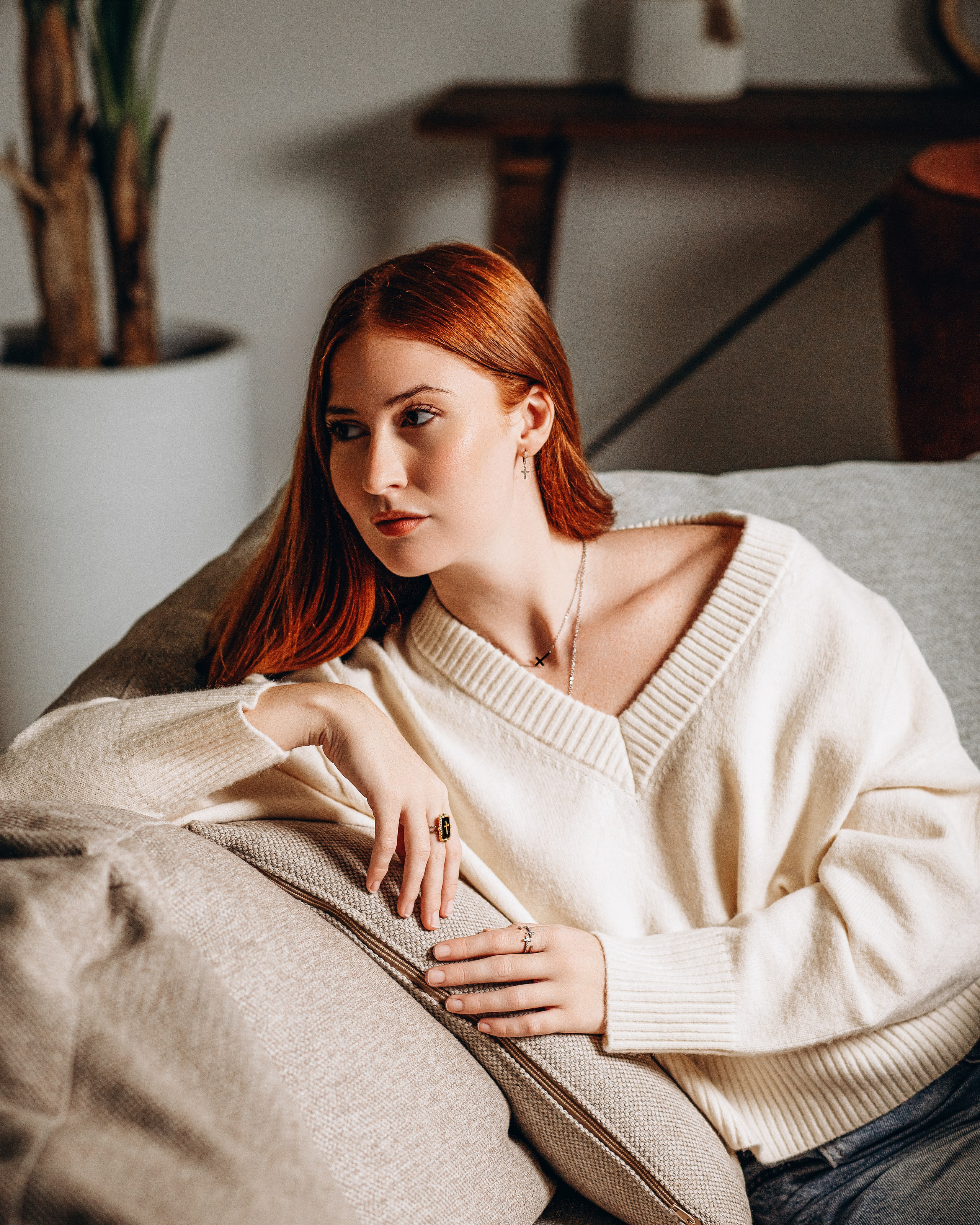 Stylish red-haired woman wearing cozy knitwear and elegant jewelry, captured in a relaxed indoor brand photoshoot in Valencia, Spain — perfect for showcasing lifestyle content, fashion accessories, and product photography for brands looking to build visual identity across Spain.