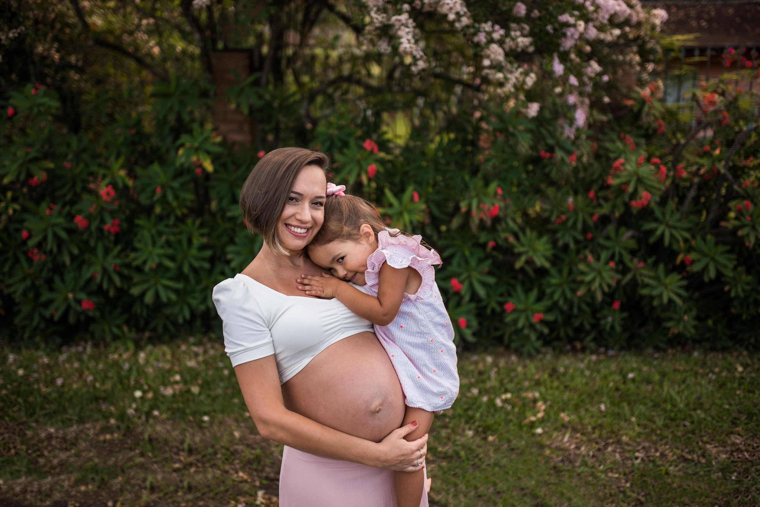 Fotografia gestante com filha em Juiz de Fora, mãe e filha se abraçando em jardim com flores