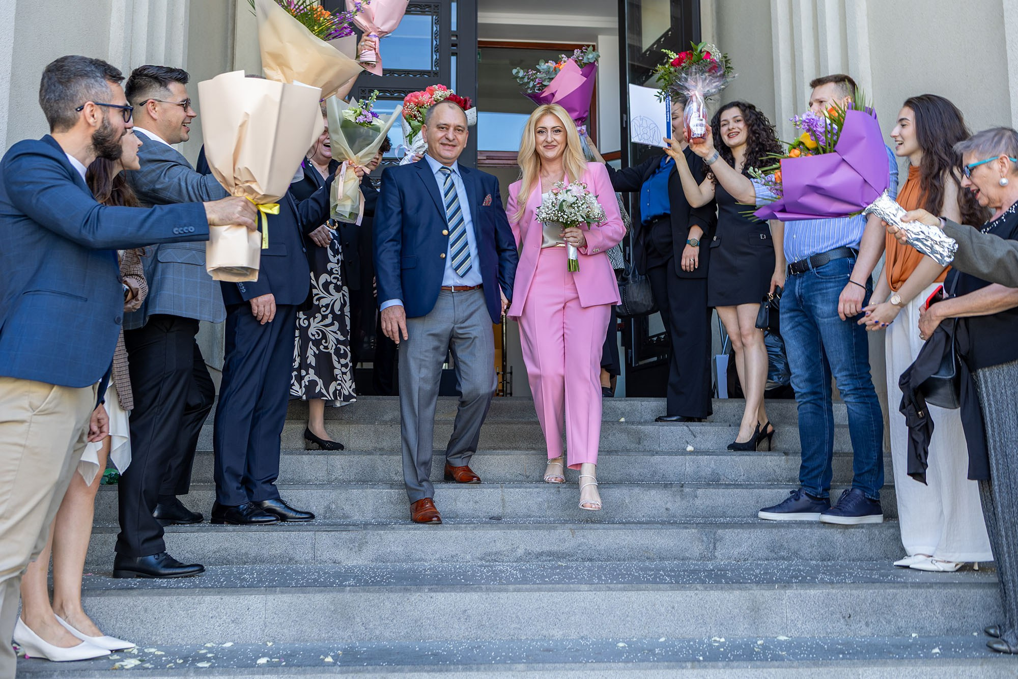 Marius și Daniela ies de la Primăria Sectorului 1, întâmpinați cu flori de familie și invitați.