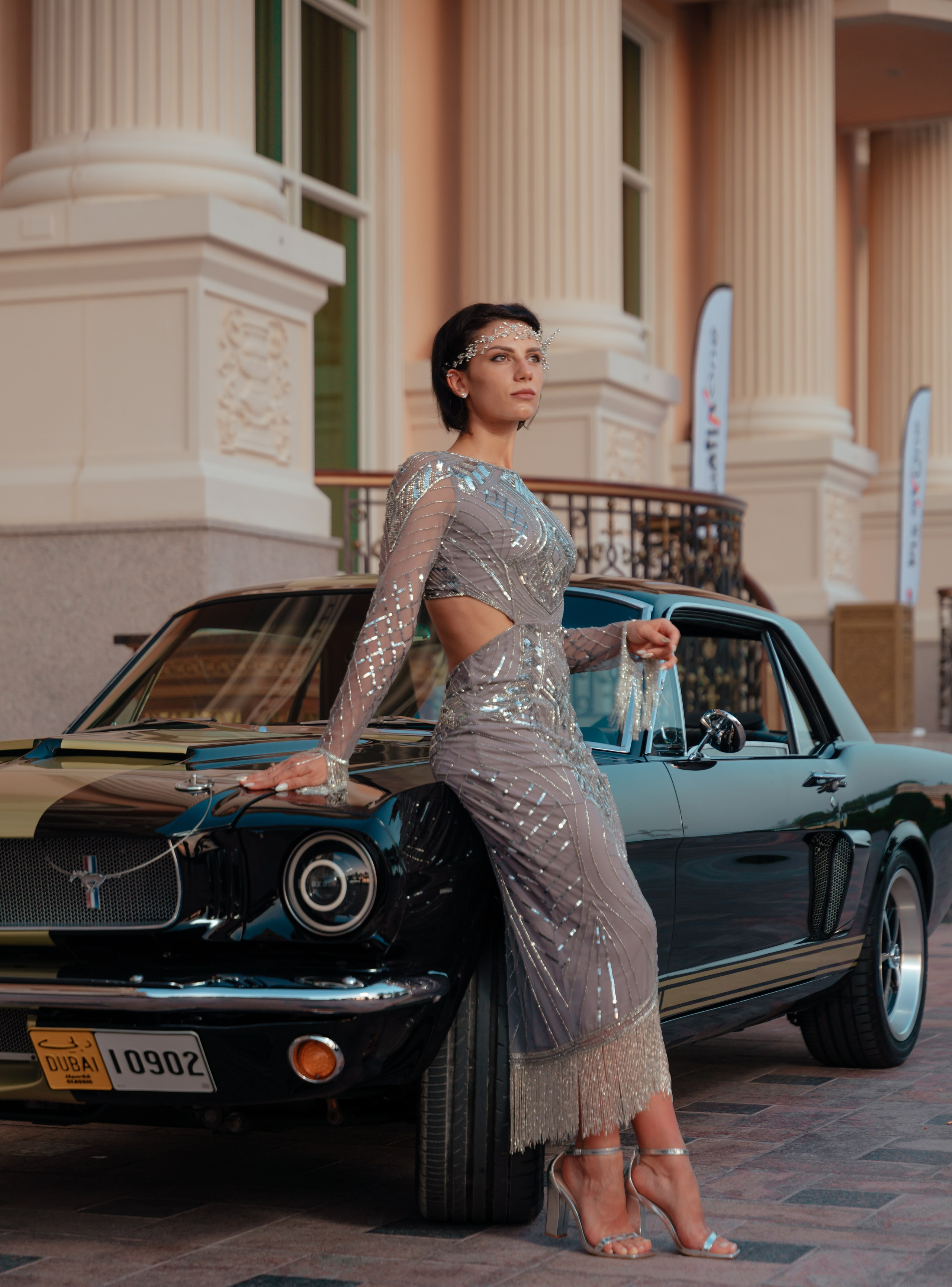 A beautiful model sits on the hood. Vintage exclusive retro car. Against the background of a Dubai building