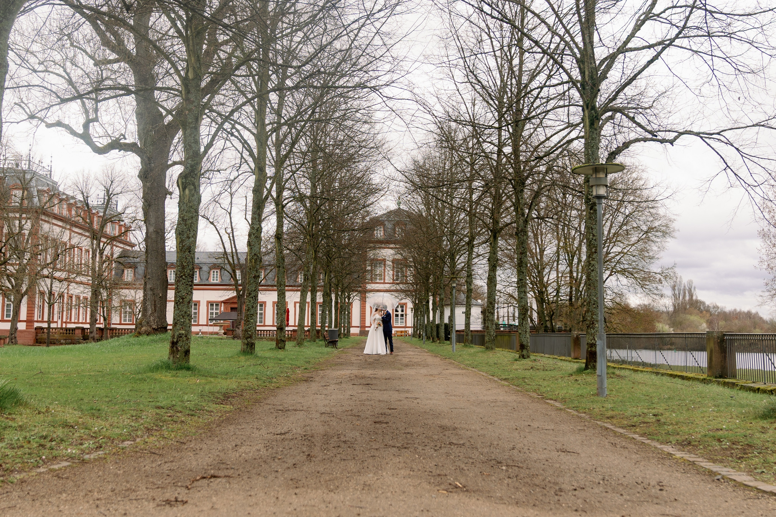Brautpaar läuft Hand in Hand durch den Schlosspark