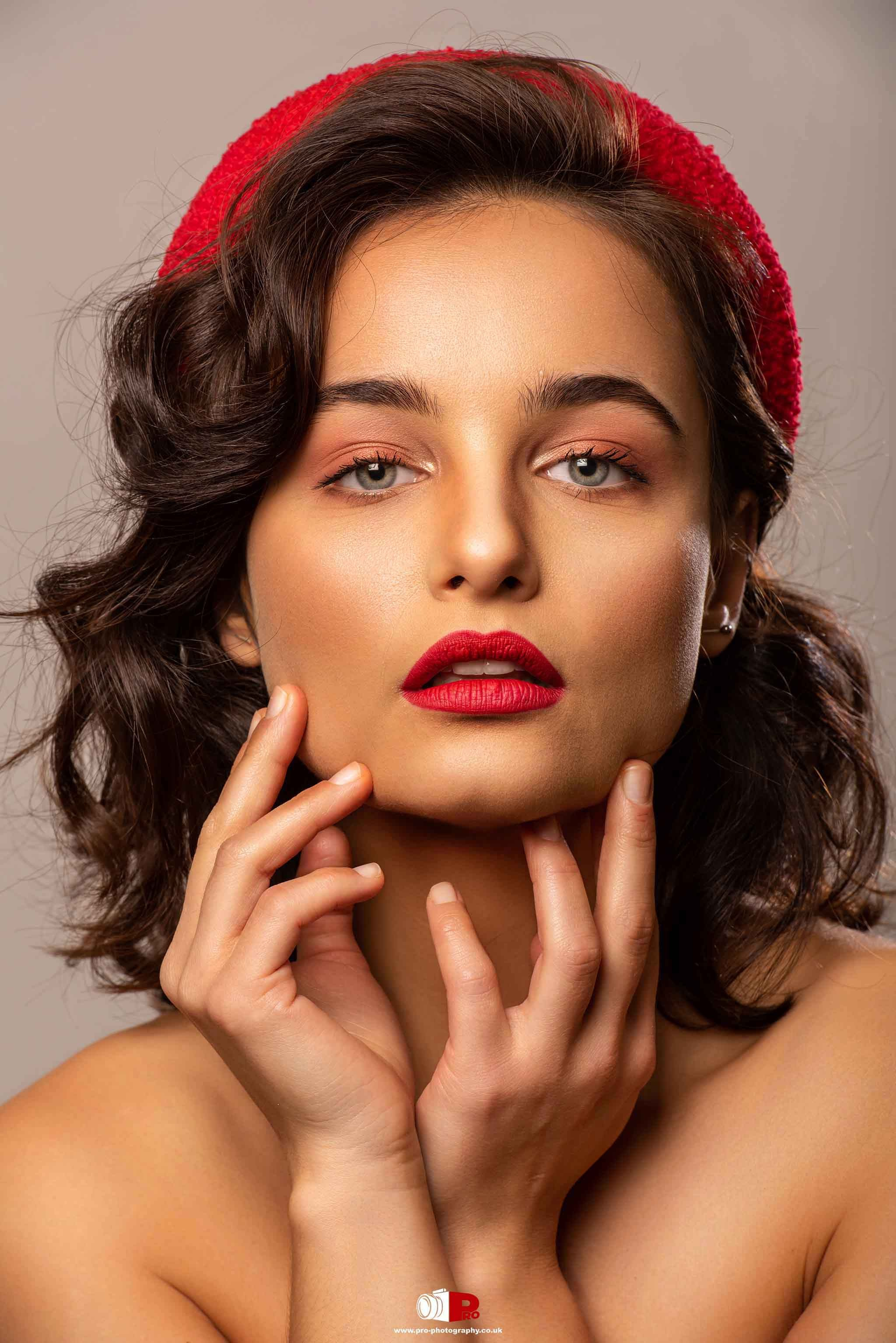 Close-up portrait of a stylish woman with red lipstick and a red beret in a fashion shoot.