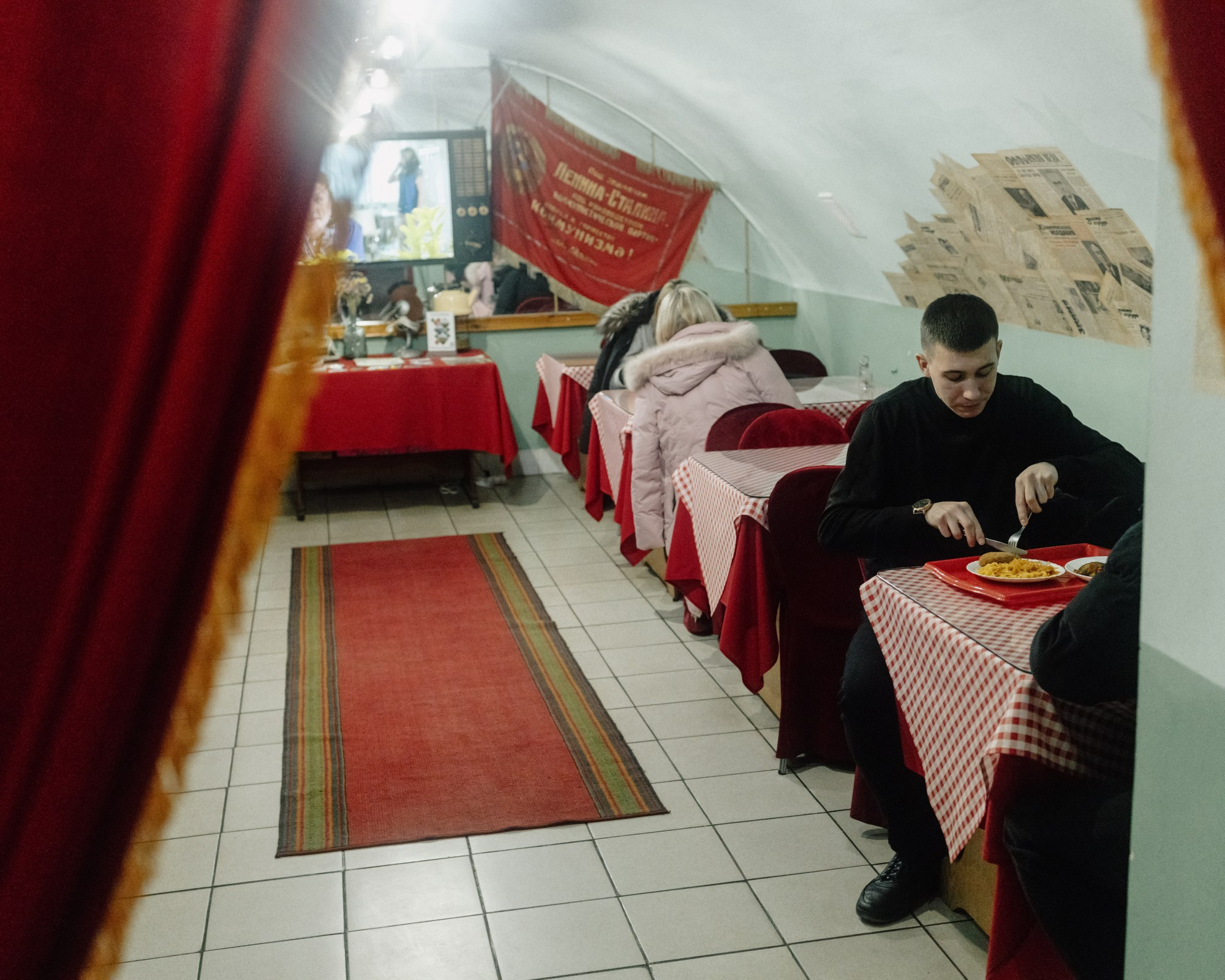 A young man eats at “USSR Stolovaya,” a Soviet-style canteen in Tiraspol. The canteen features decorations and elements from the Soviet era, including newspapers on the walls.
